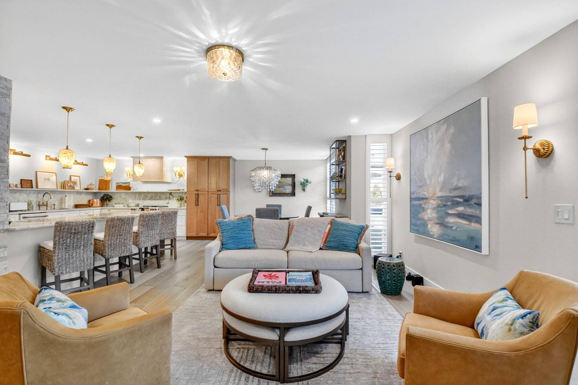 Open-concept interior featuring light wood-finish flooring, recessed lighting, brass-finish wall sconces, a built-in floor-to-ceiling wooden cabinet, and decorative glass pendant lighting