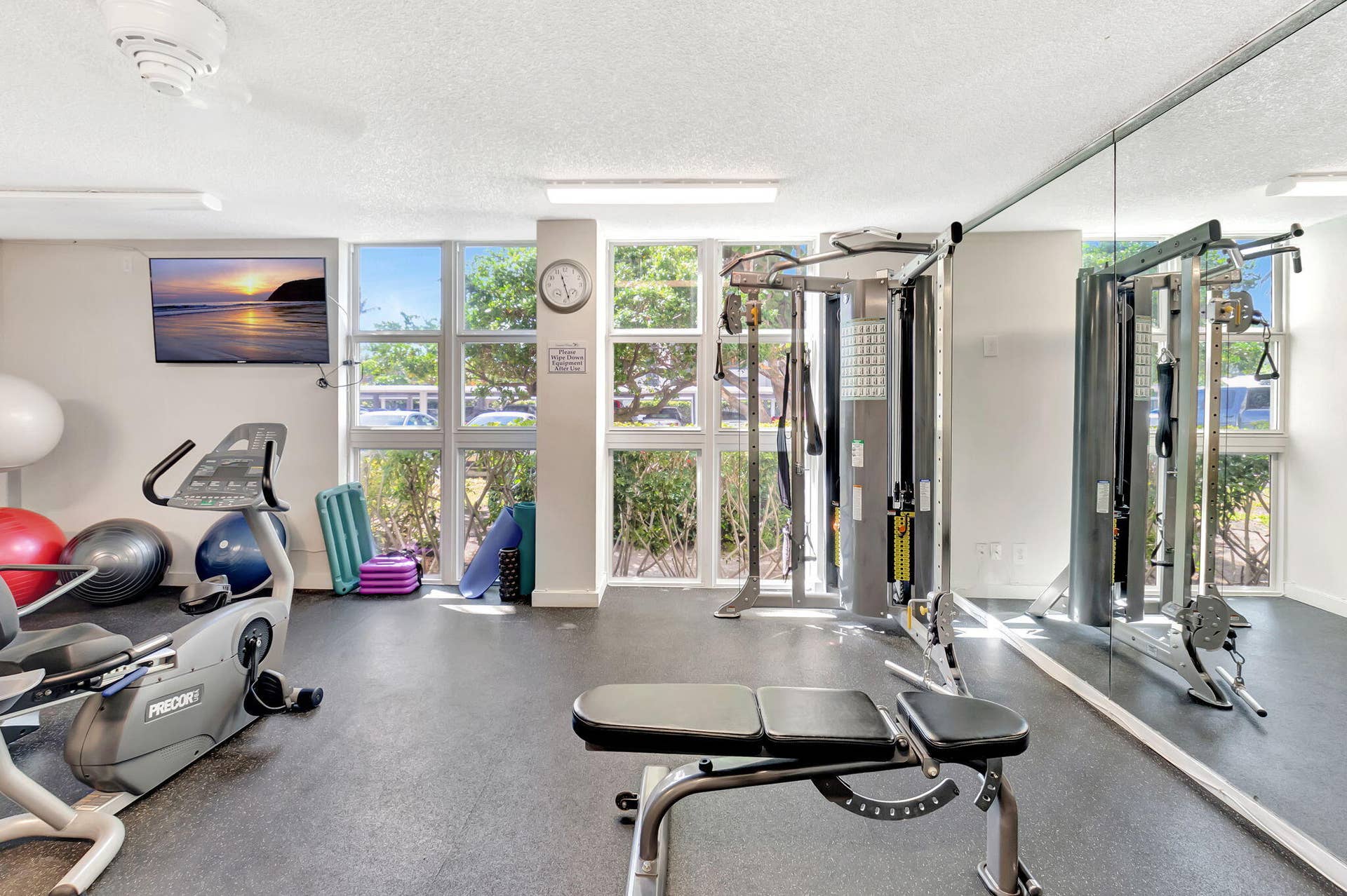 Fitness center featuring full-wall mirrors, multi-panel windows, and durable rubberized flooring