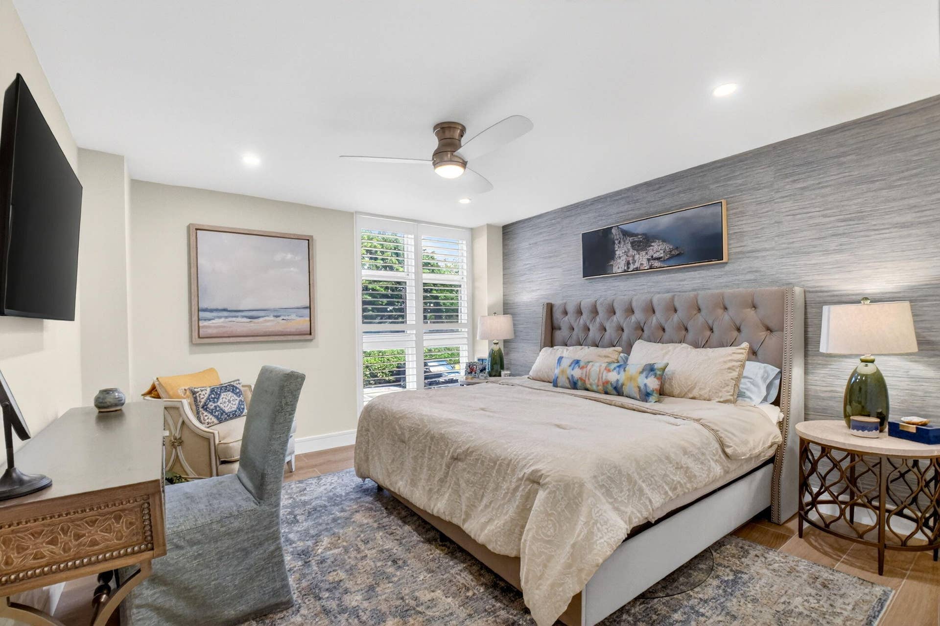 Textured grey accent wall, ceiling-mounted fan, and shutter-style window coverings