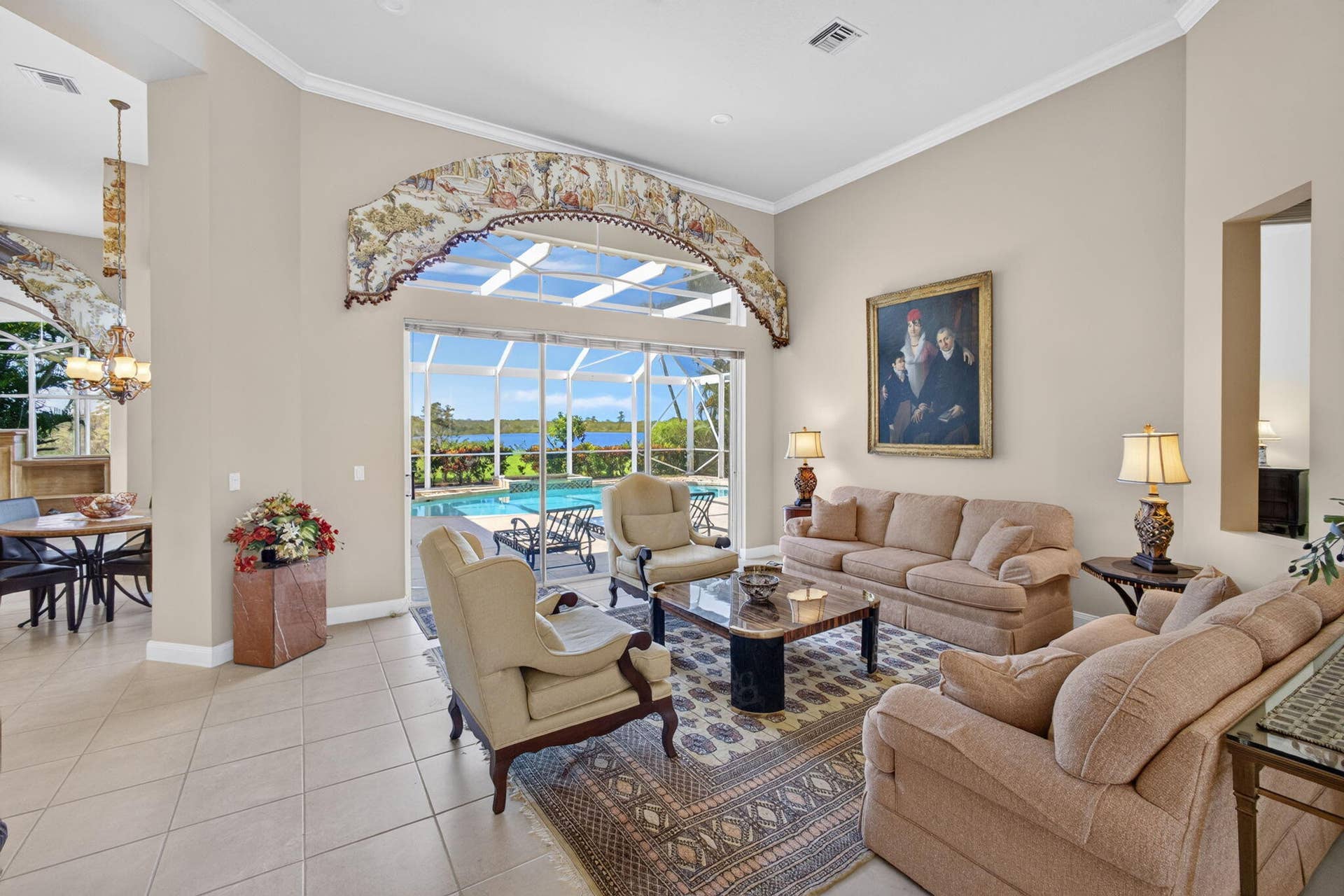 42 Windward Isle, Palm Beach Gardens, FL 33418 Living area featuring high ceilings, large arched decorative detailing above sliding glass doors, neutral tile flooring, and recessed lighting