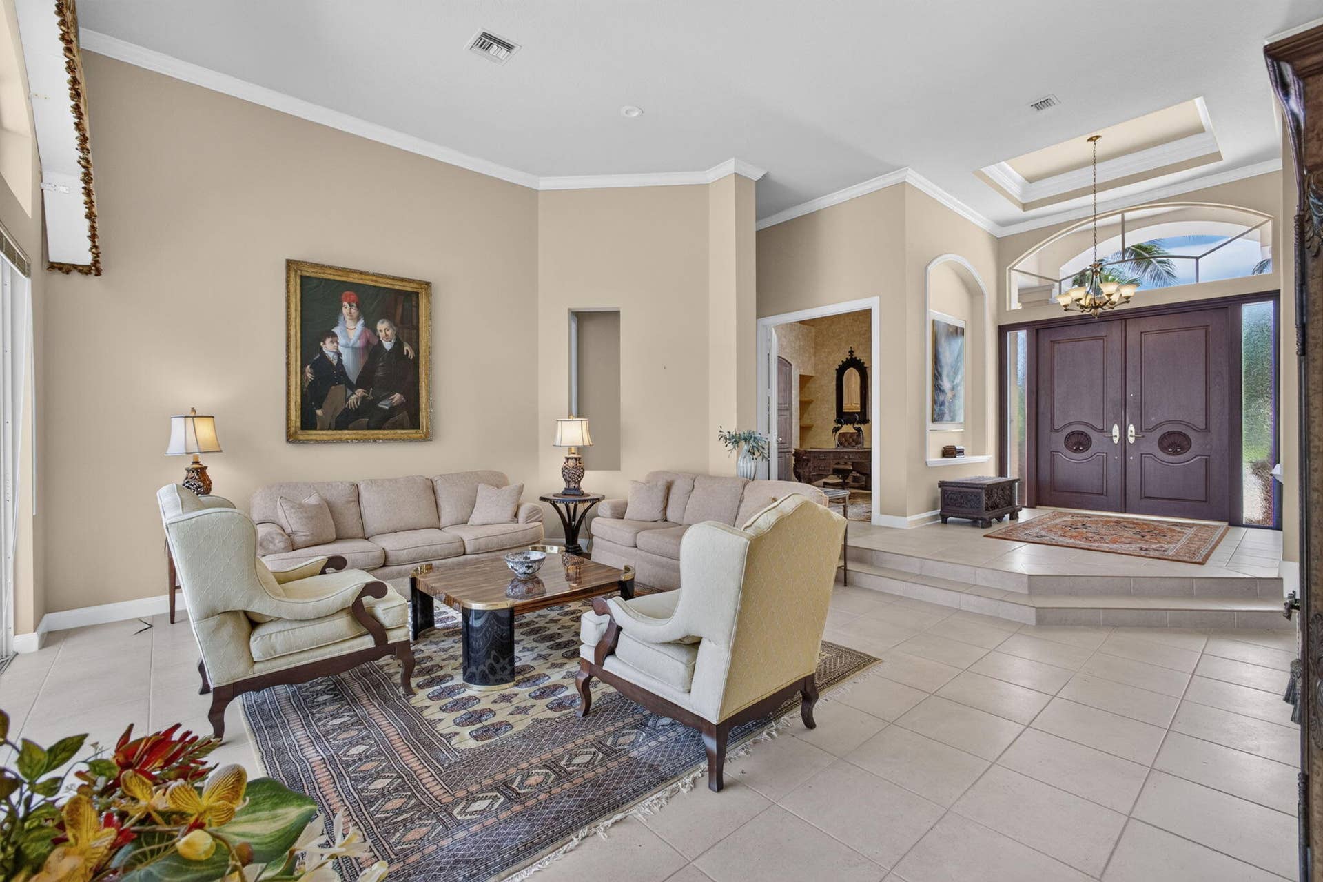 42 Windward Isle, Palm Beach Gardens, FL 33418 High-ceiling living area featuring large-format tile flooring, double-door entryway, arched transom window, and recessed ceiling niche