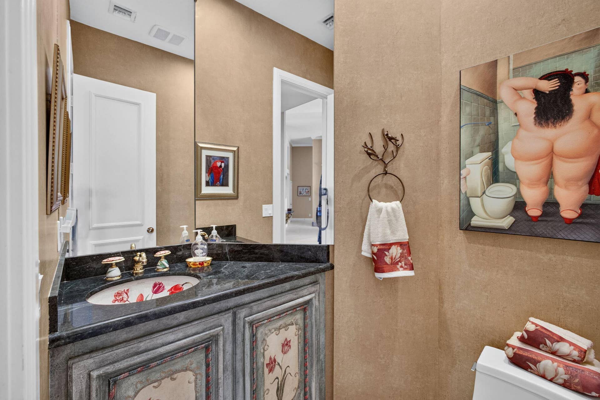 42 Windward Isle, Palm Beach Gardens, FL 33418 Custom vanity featuring decorative hand-painted floral panels, dark stone countertop, integrated oval sink, and ornate gold-tone faucet