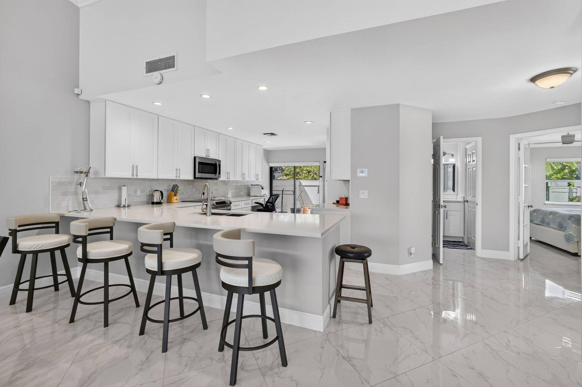 543 Prestwick Circle, Palm Beach Gardens, FL 33418 Kitchen featuring white cabinetry, solid-surface countertops with a breakfast bar, recessed lighting, and large-format tile flooring