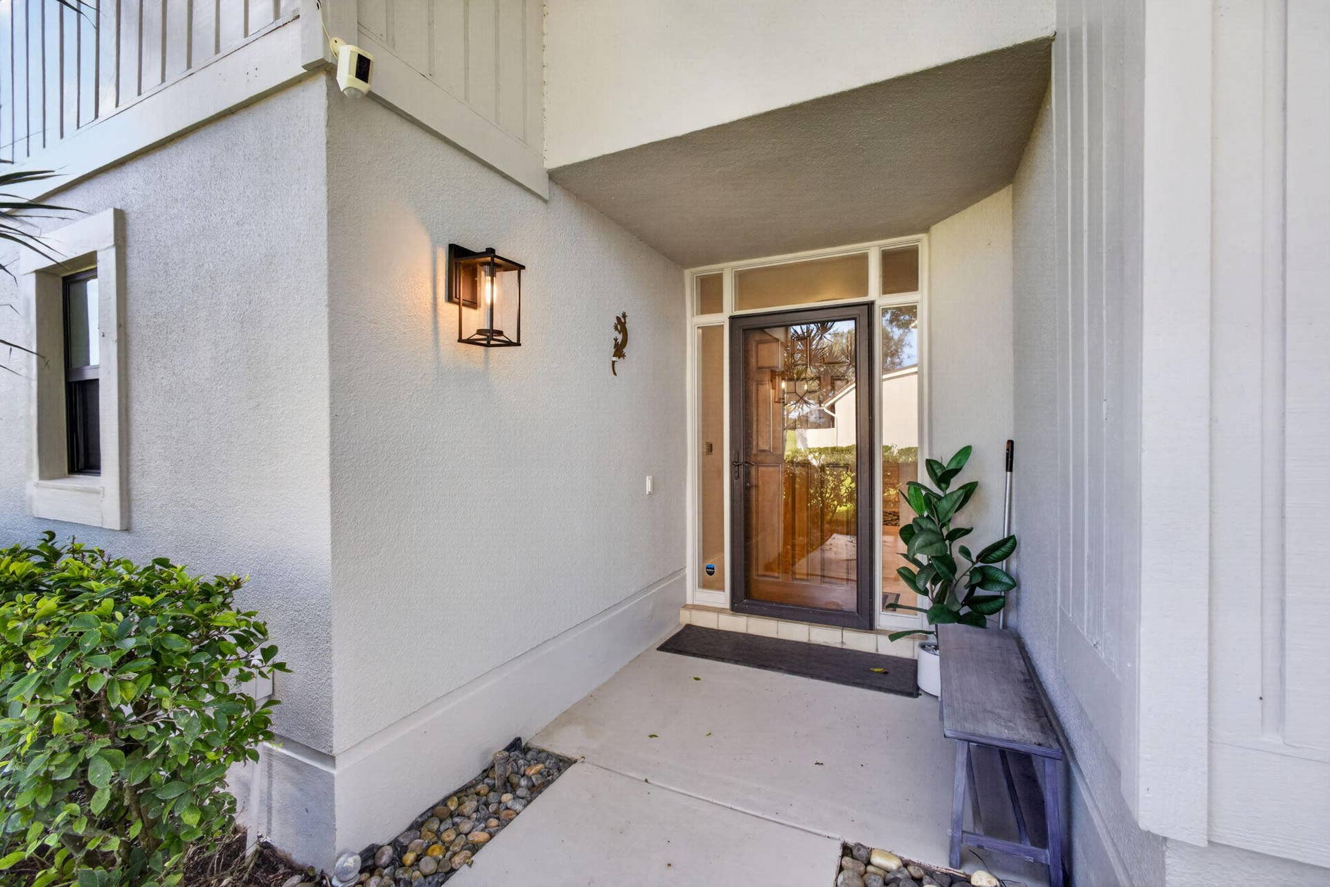 543 Prestwick Circle, Palm Beach Gardens, FL 33418 Covered entryway featuring a framed glass front door, transom window, and matte black exterior wall lantern
