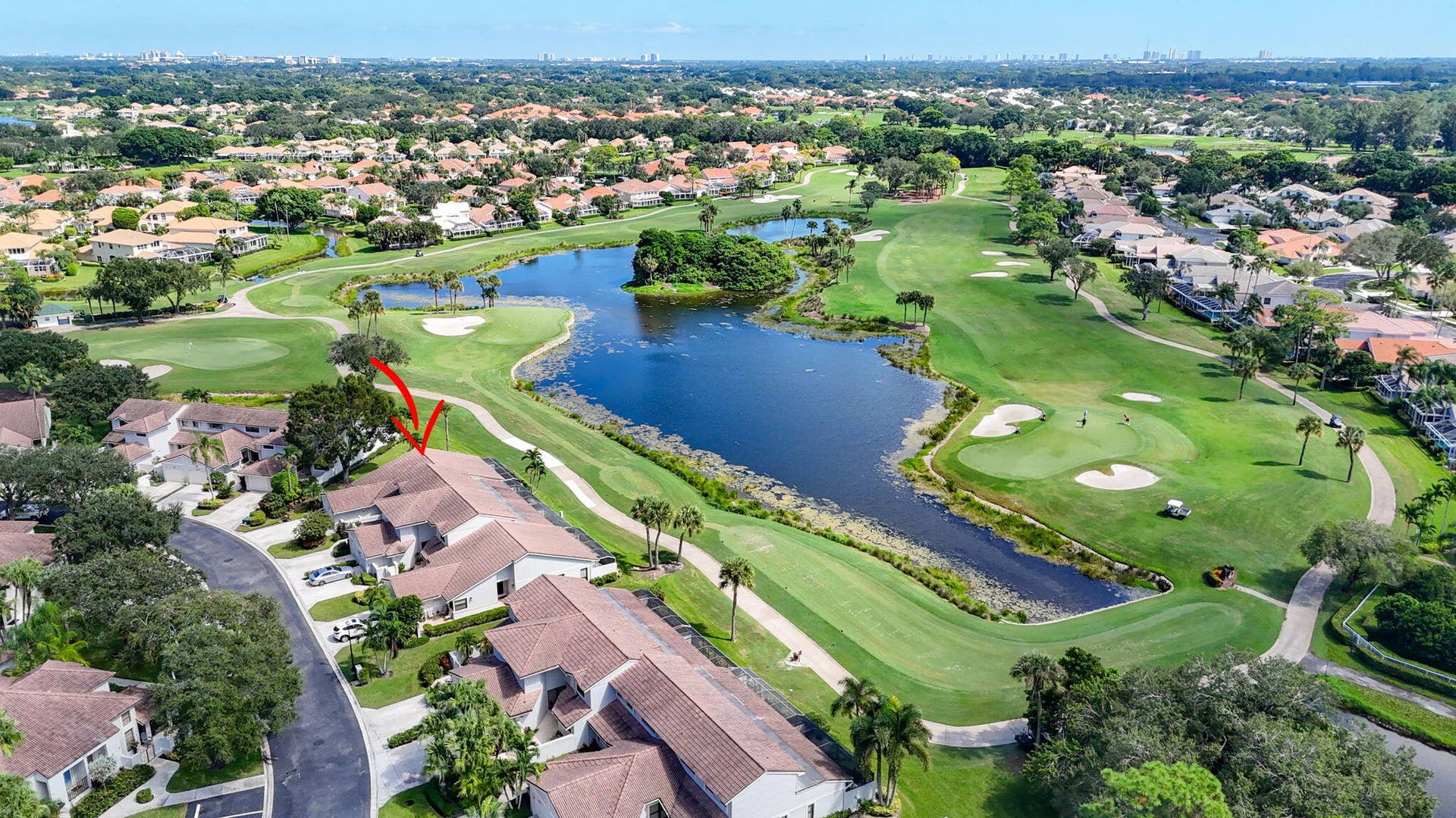 543 Prestwick Circle, Palm Beach Gardens, FL 33418 Aerial perspective of a multi-unit residential structure featuring tile roofing, situated on a golf course lot with water features, sand bunkers, and manicured fairways