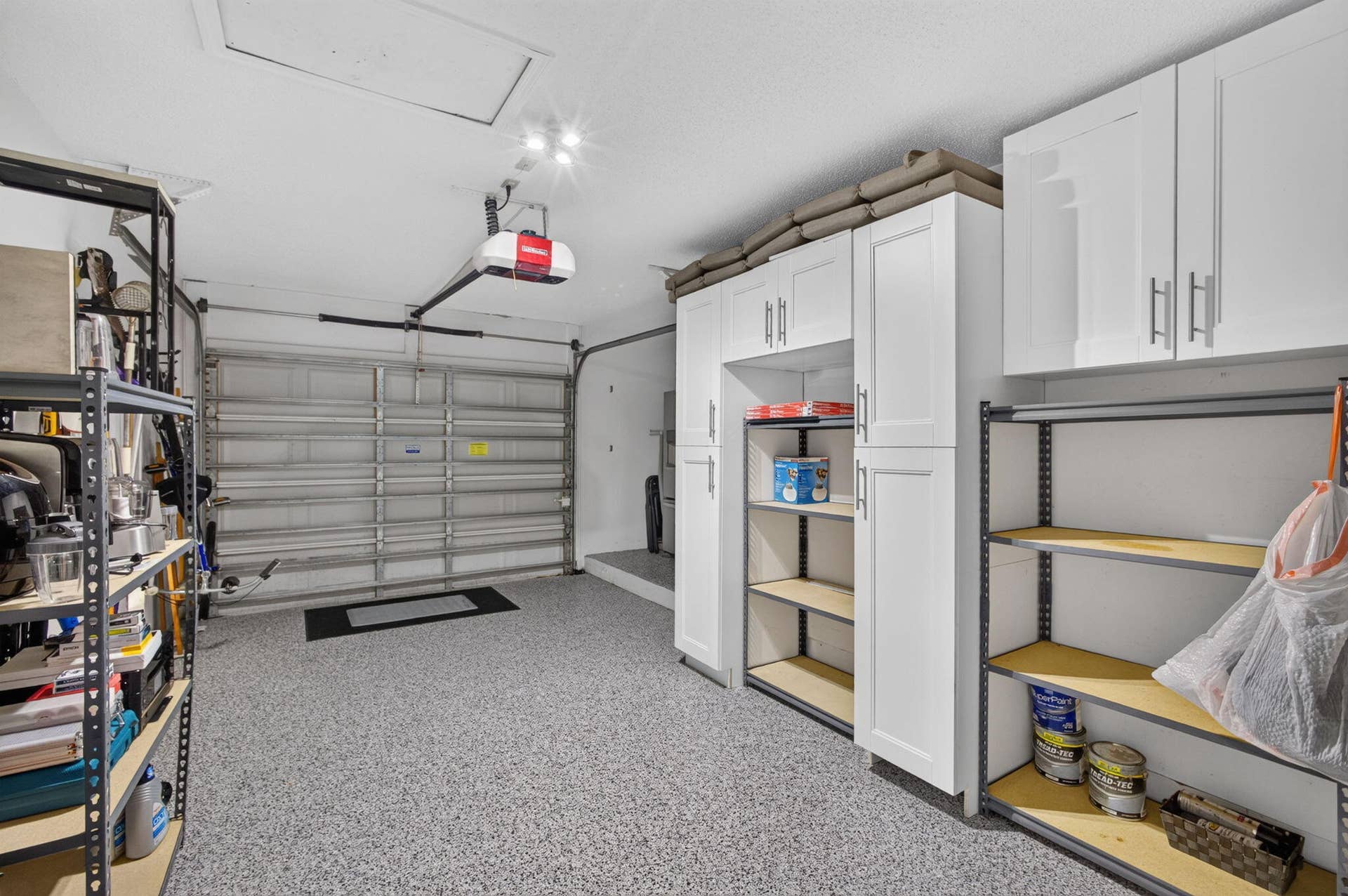 543 Prestwick Circle, Palm Beach Gardens, FL 33418 Garage featuring an epoxy-coated floor, integrated white cabinetry with shaker-style doors, and metallic hardware