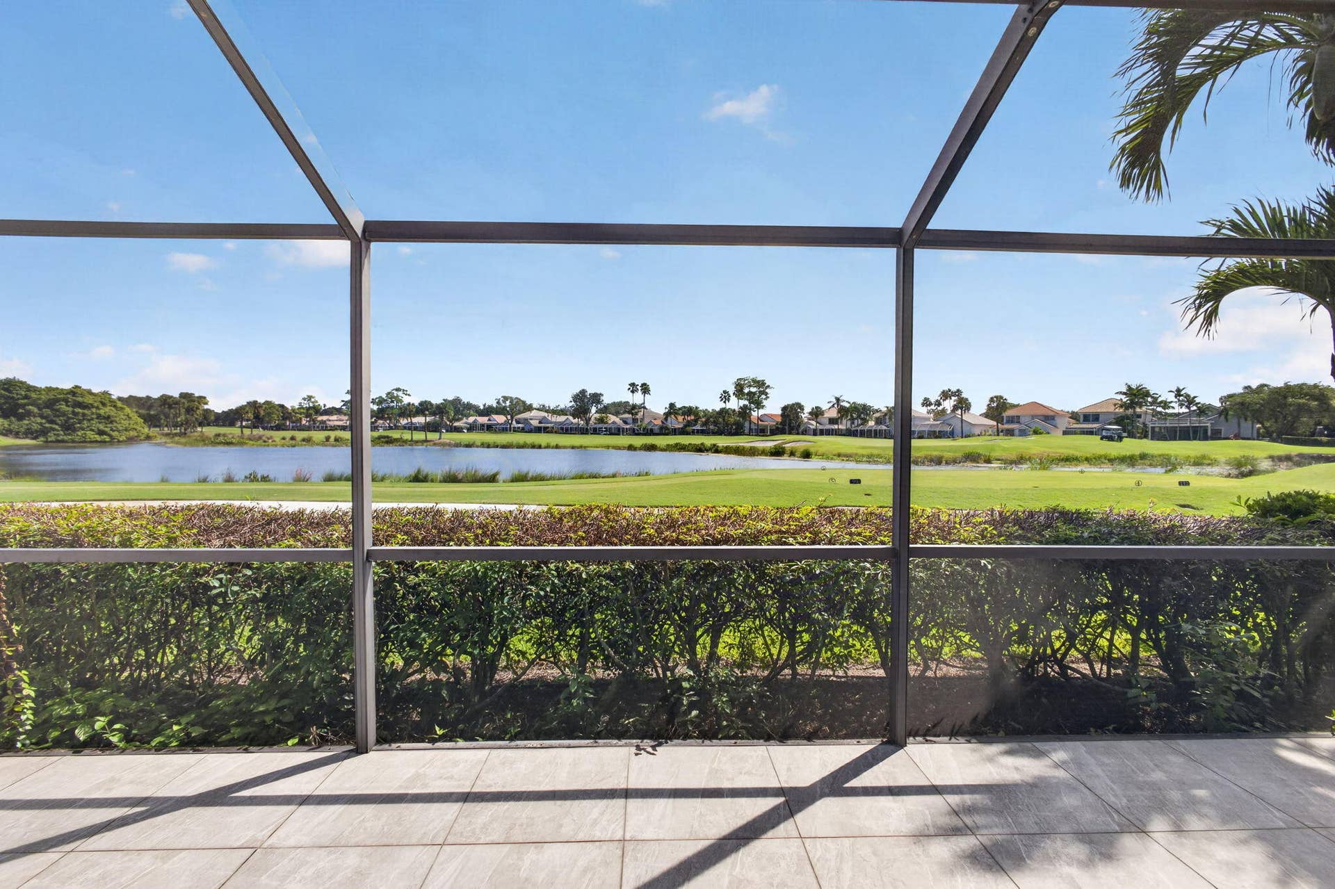 543 Prestwick Circle, Palm Beach Gardens, FL 33418 Screened-in lanai with tile flooring, mature landscaping, and an expanse overlooking a water feature and golf course