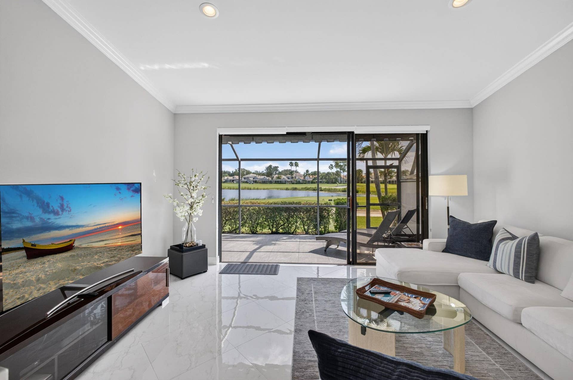543 Prestwick Circle, Palm Beach Gardens, FL 33418 Large-format tile flooring, recessed lighting, crown molding, and sliding glass doors leading to a screened-in lanai overlooking a lake
