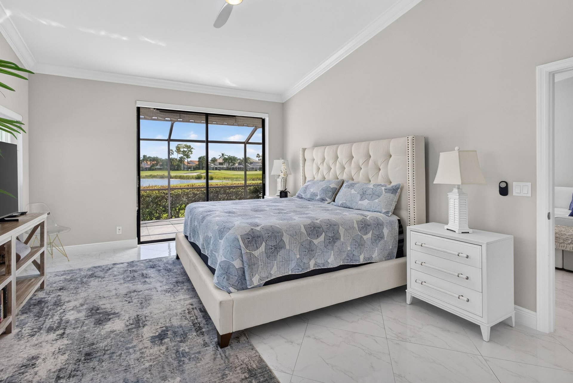 543 Prestwick Circle, Palm Beach Gardens, FL 33418 Vaulted ceiling with crown molding, large-format tile flooring, and sliding glass doors leading to a screened-in lanai