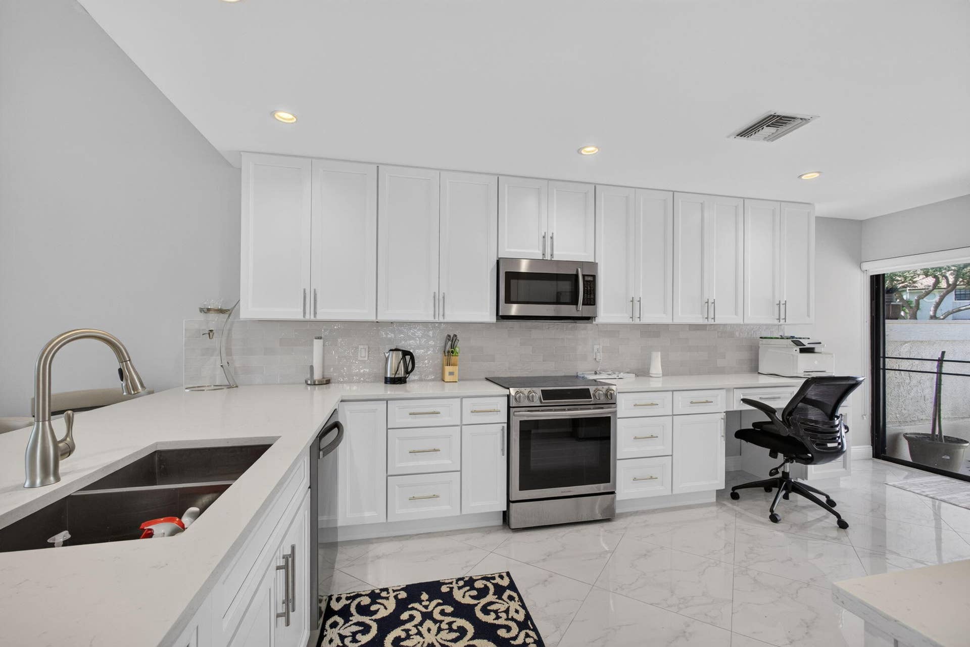 543 Prestwick Circle, Palm Beach Gardens, FL 33418 Kitchen featuring white shaker-style cabinetry, quartz countertops, subway tile backsplash, stainless steel appliances, and large-format tile flooring