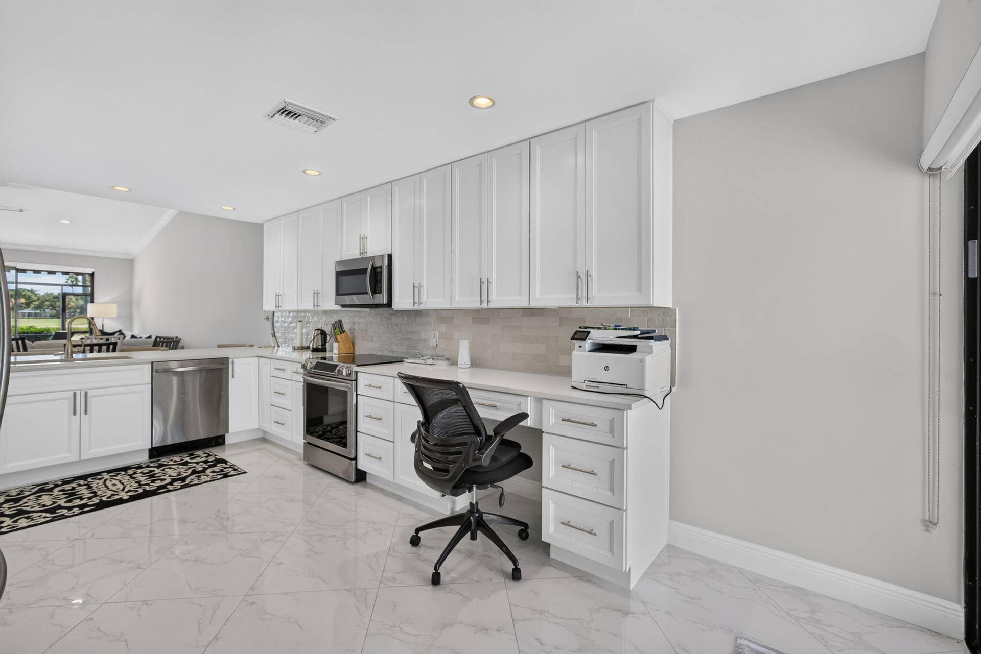 543 Prestwick Circle, Palm Beach Gardens, FL 33418 Kitchen featuring white cabinetry, solid-surface countertops, tile backsplash, stainless steel appliances, and polished tile flooring