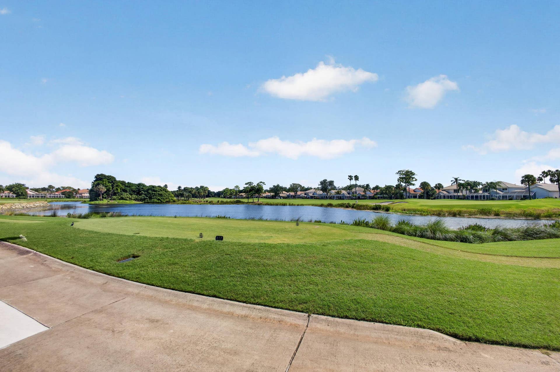 543 Prestwick Circle, Palm Beach Gardens, FL 33418 Waterfront property grounds featuring a manicured grass lawn, concrete walkway, and pond