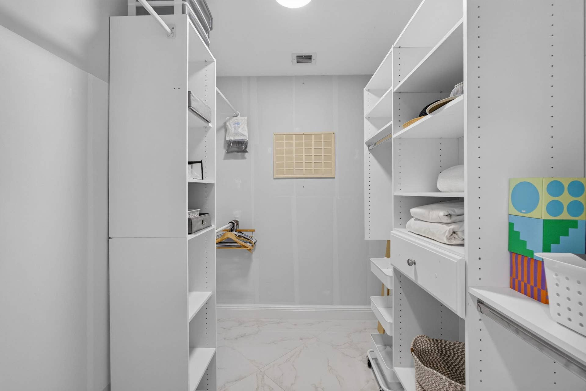 543 Prestwick Circle, Palm Beach Gardens, FL 33418 Custom walk-in closet featuring white built-in shelving, integrated hanging rods, a dedicated drawer unit, and tile flooring