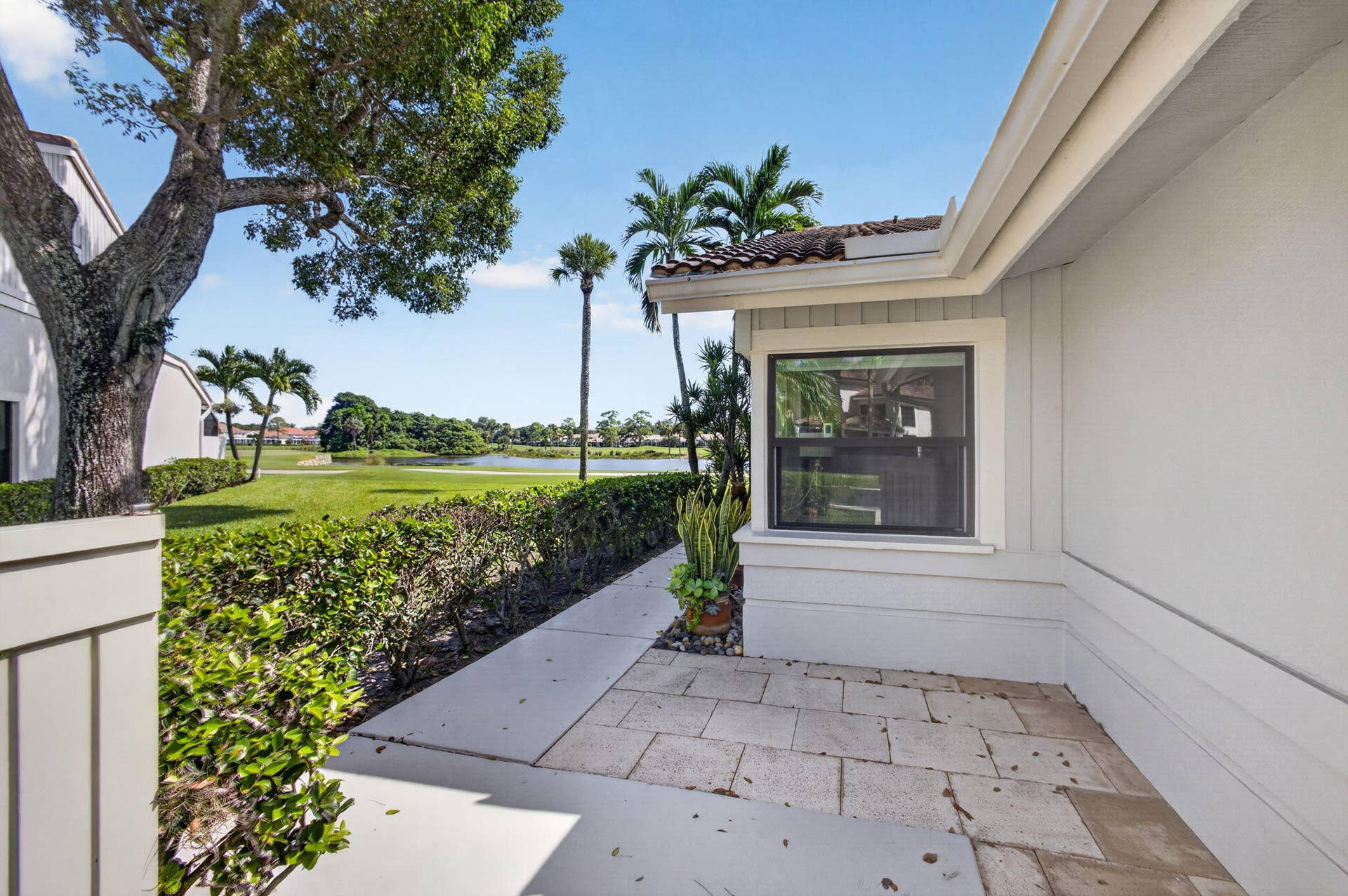 543 Prestwick Circle, Palm Beach Gardens, FL 33418 Exterior patio featuring stone pavers, tile roofing, and integrated landscaping with mature trees