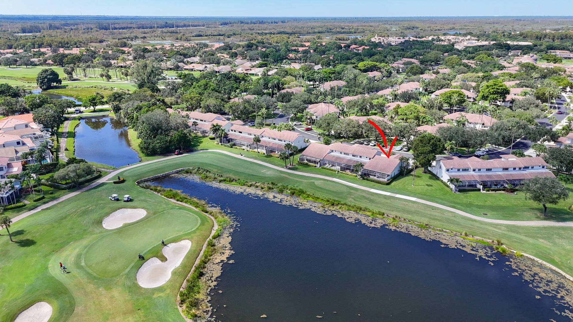 543 Prestwick Circle, Palm Beach Gardens, FL 33418 Aerial perspective of a multi-unit residential building positioned on a golf course featuring water hazards, sand bunkers, and manicured grounds