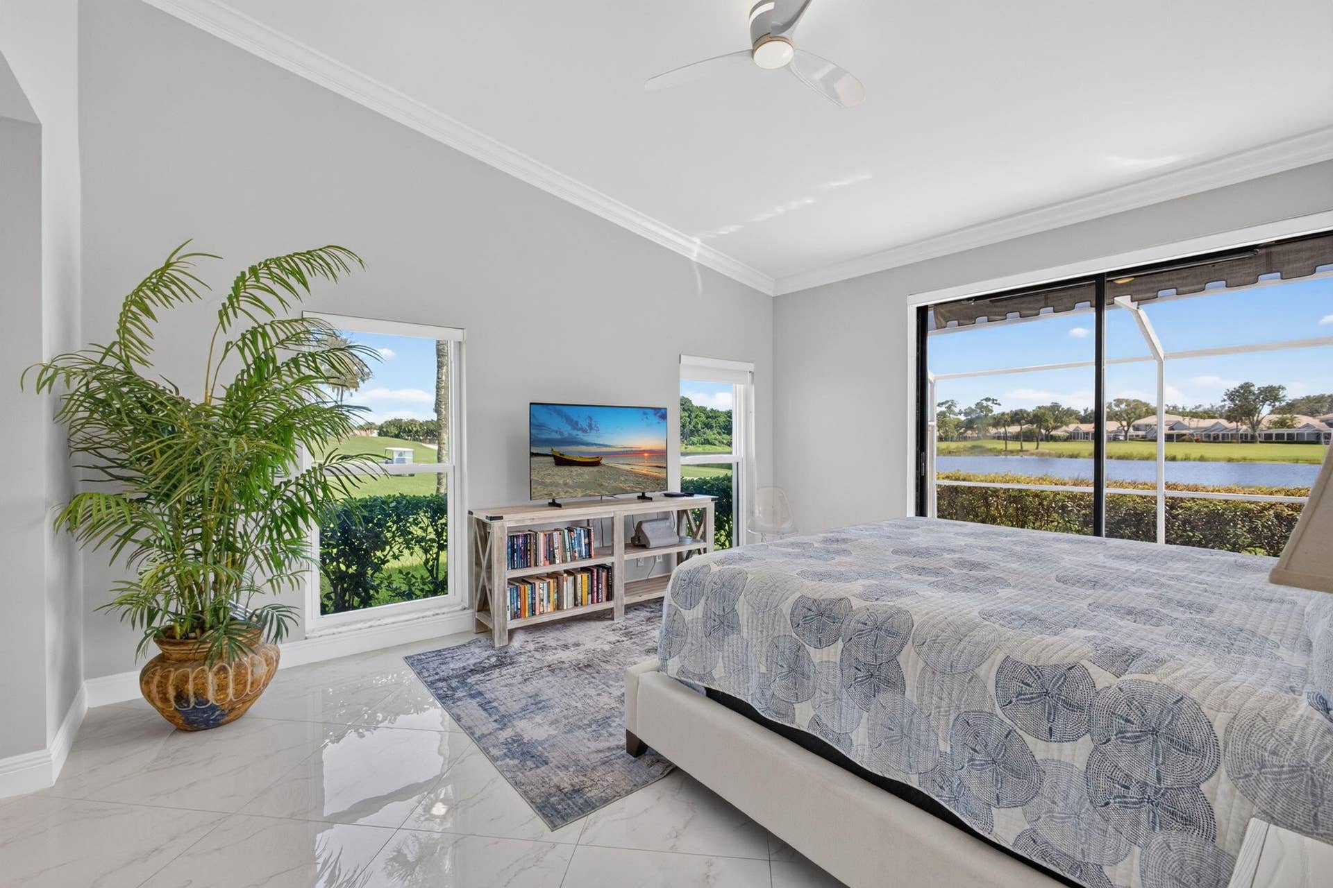 543 Prestwick Circle, Palm Beach Gardens, FL 33418 Vaulted ceiling, neutral wall tones, large-format tile flooring, ceiling fan, and sliding glass doors with exterior water scenery