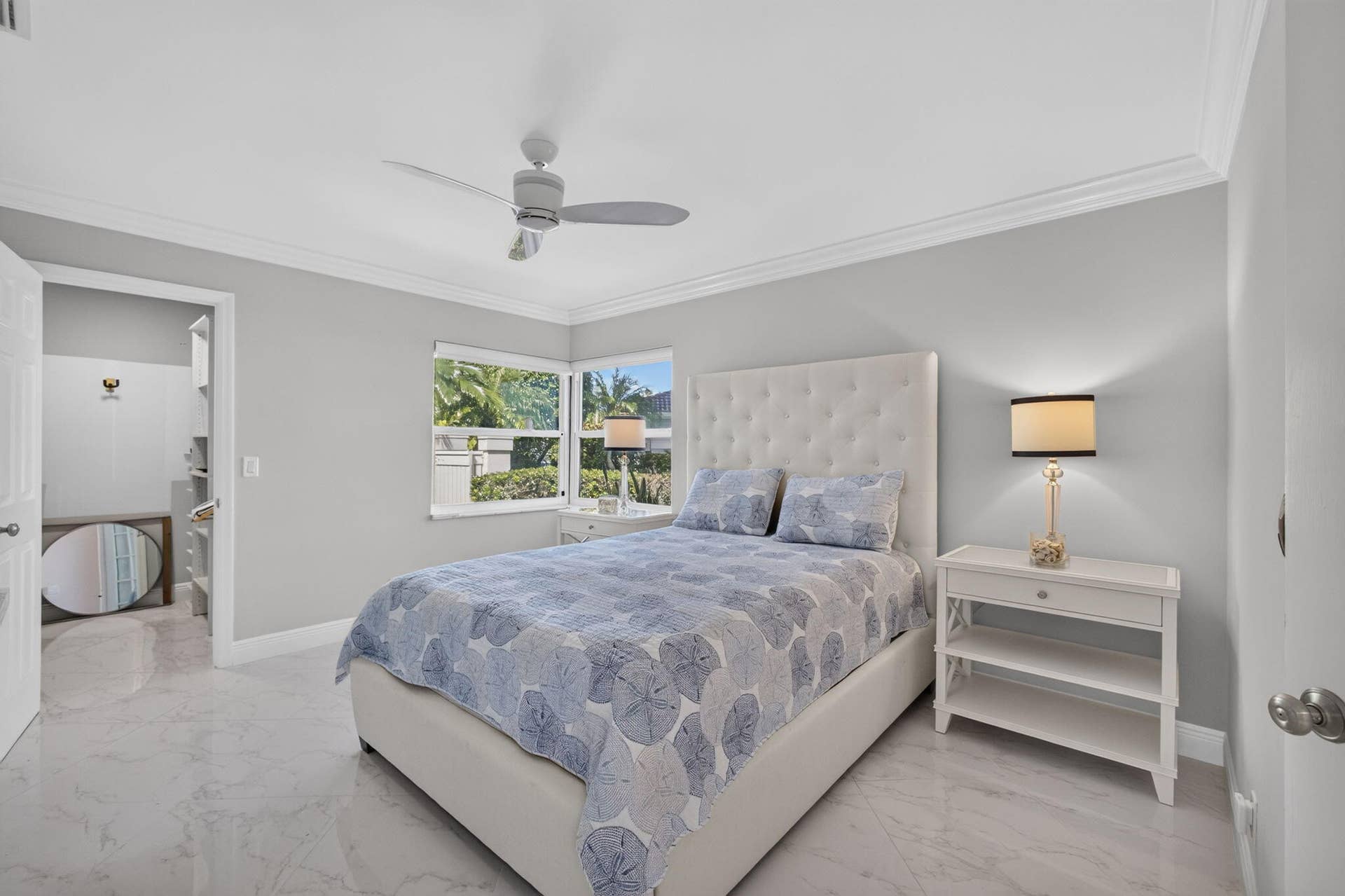 543 Prestwick Circle, Palm Beach Gardens, FL 33418 Room featuring polished stone-finish flooring, crown molding, a central ceiling fan, and corner windows with exterior greenery