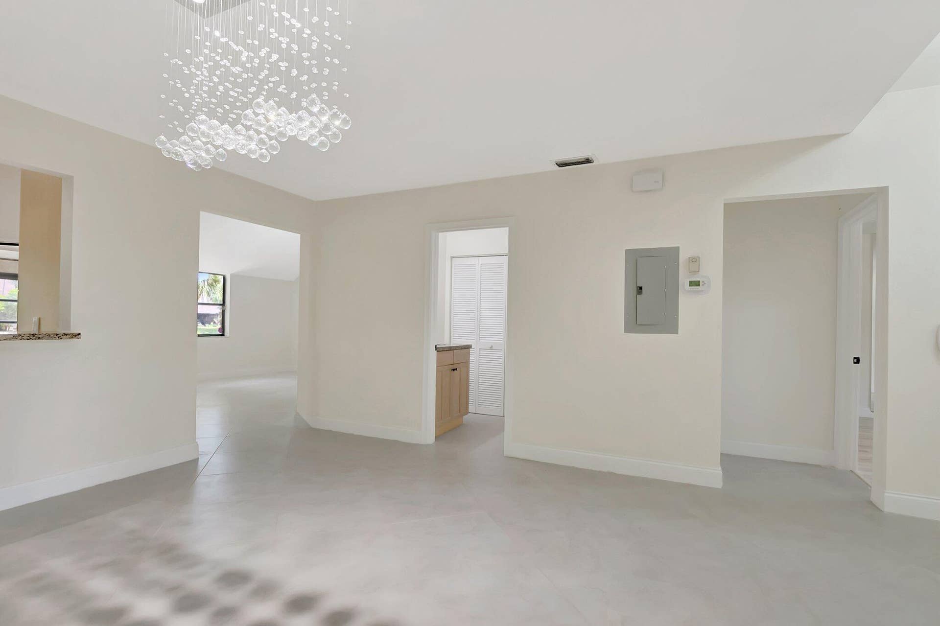 Interior space featuring neutral wall tones, large-format tile flooring, a multi-tiered crystal-style chandelier, and a granite-topped pass-through counter