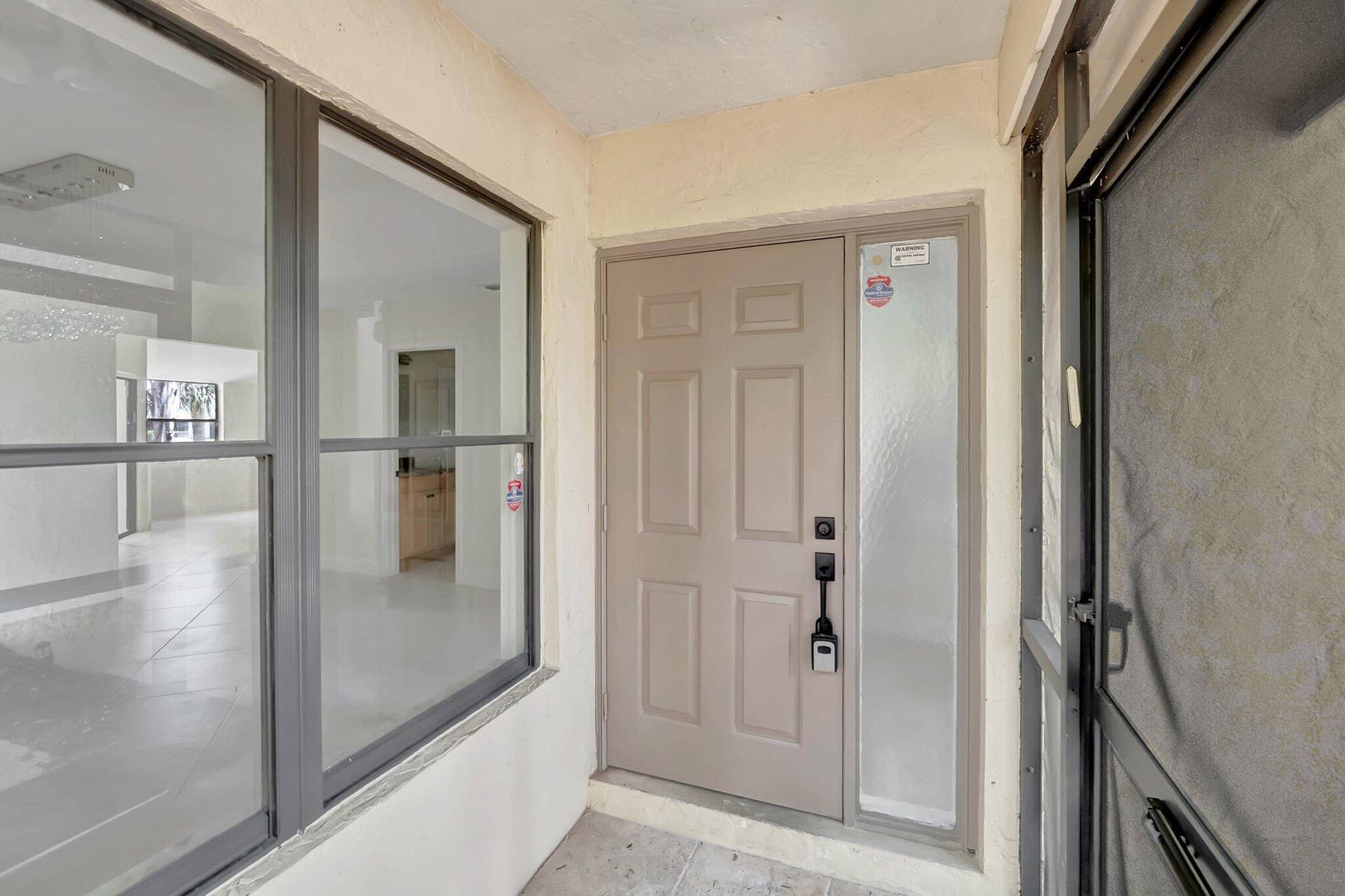 Entrance featuring a six-panel entry door with a side light, metal-framed screen door, and tile flooring