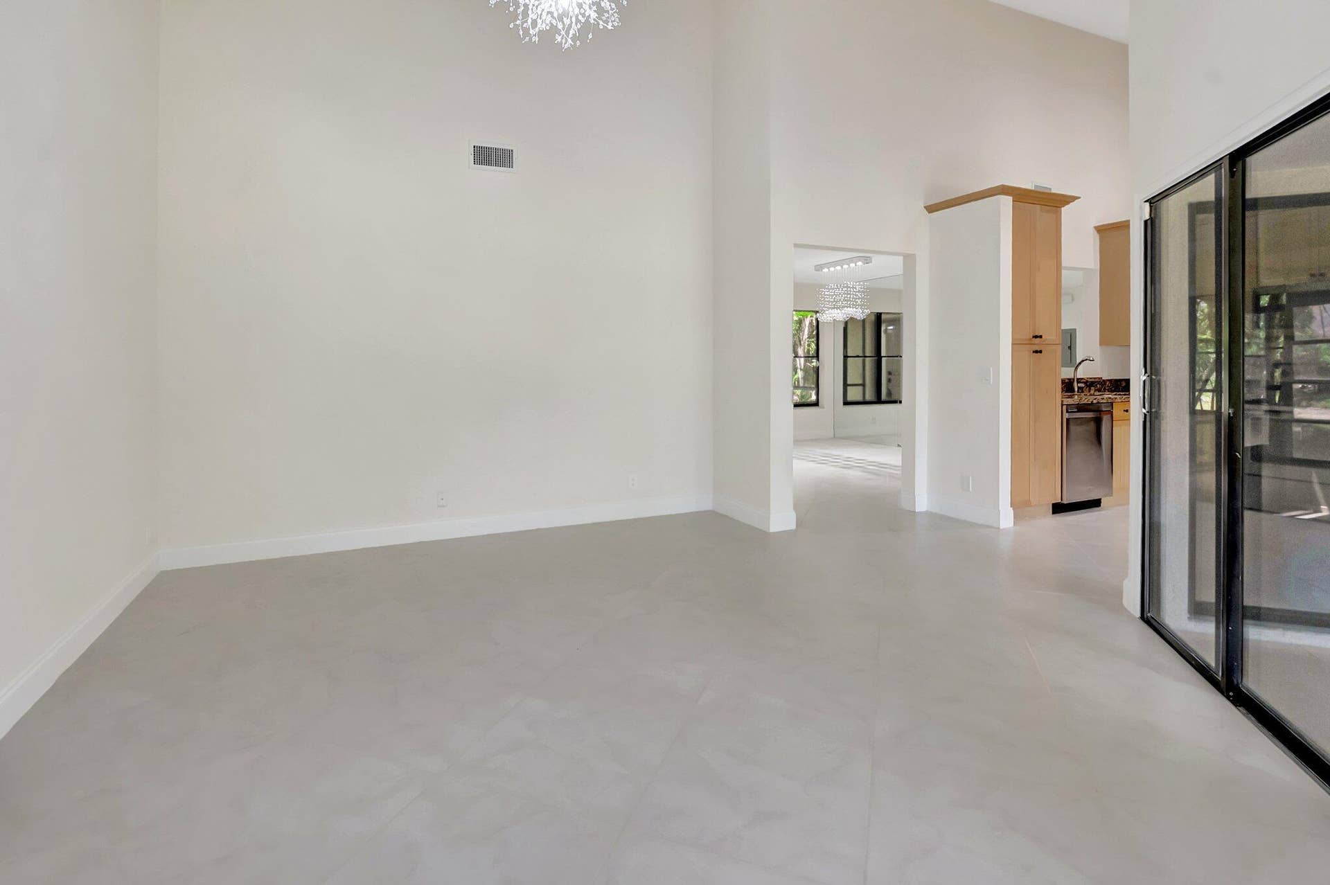 High ceilings, large-format tile flooring, recessed architectural lighting, and floor-to-ceiling sliding glass doors