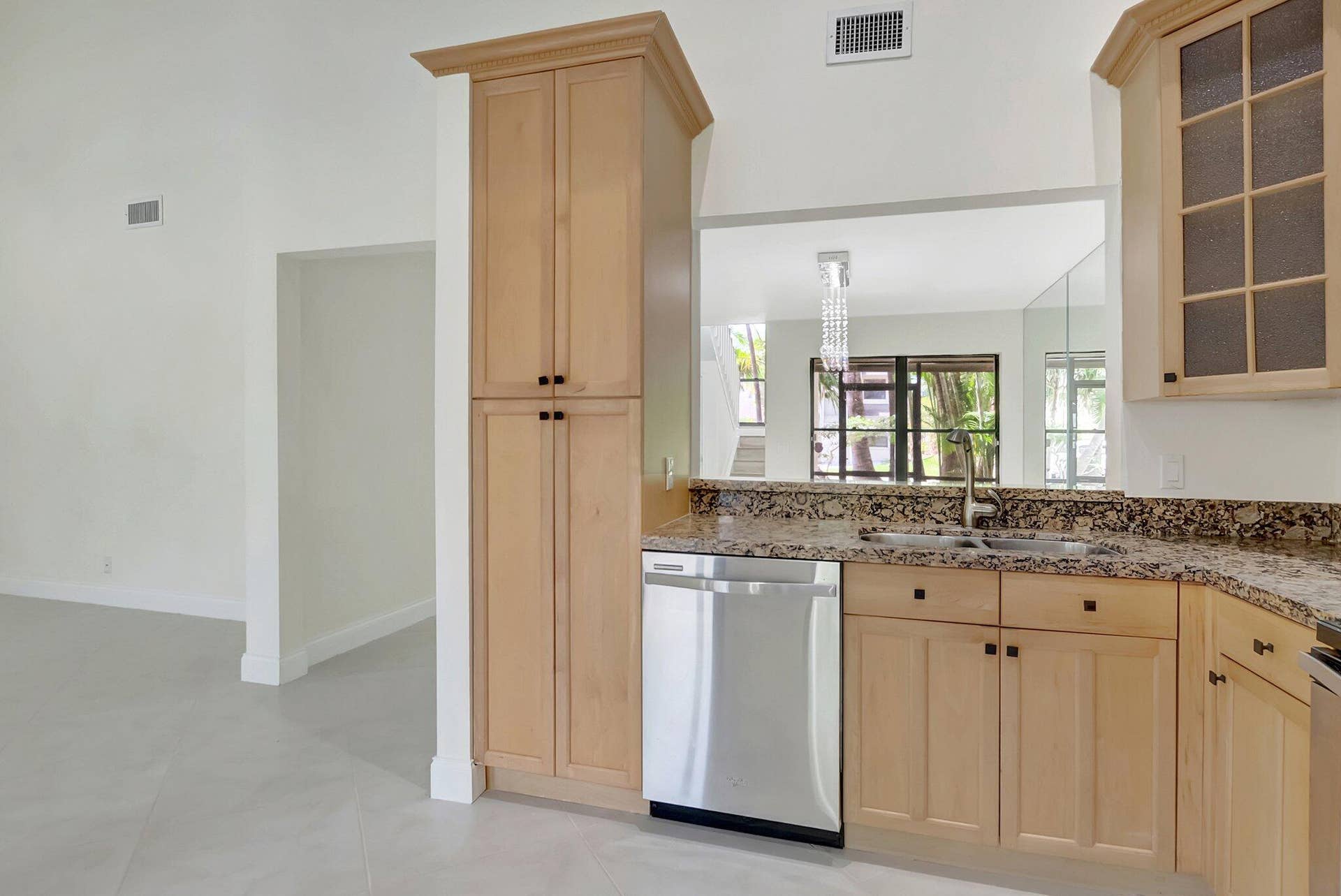 Light-finish cabinetry, stone-surface countertops, stainless steel dishwasher, double-basin sink, and glass-front upper cabinet doors