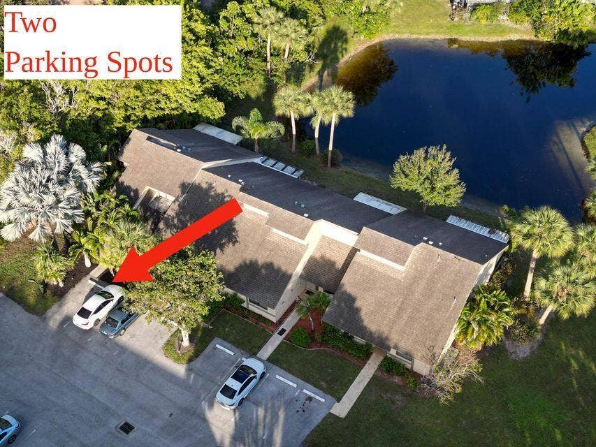 Aerial perspective of a multi-unit property featuring two dedicated surface parking spaces, a shingled roof, and direct water frontage