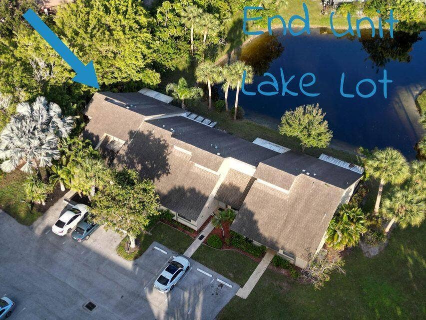 Aerial perspective of an end-unit residence situated on a lakefront lot with mature landscaping