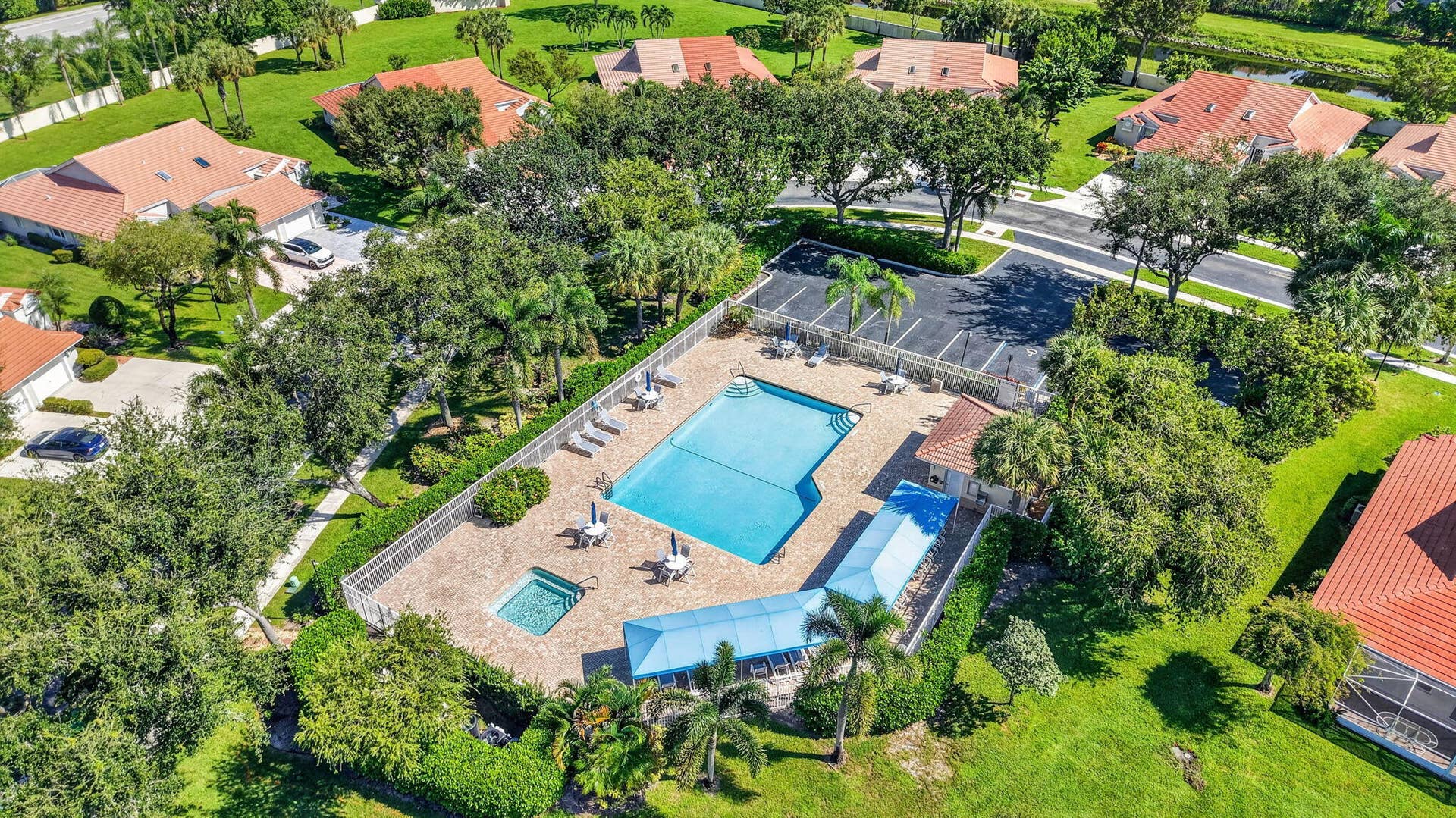 Community recreation area featuring an in-ground swimming pool, integrated spa, covered patio structure, and paved parking area