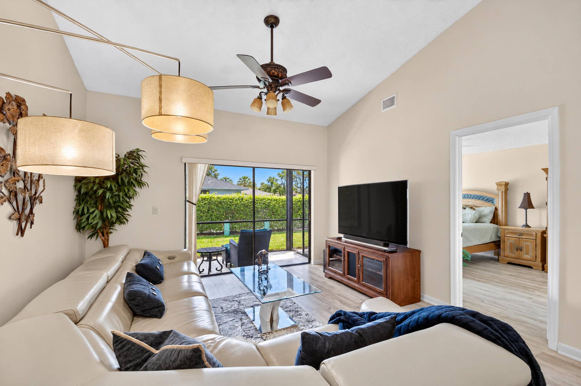 Vaulted ceiling featuring a central multi-blade ceiling fan, expansive sliding glass doors, neutral interior paint, and wood-finish flooring