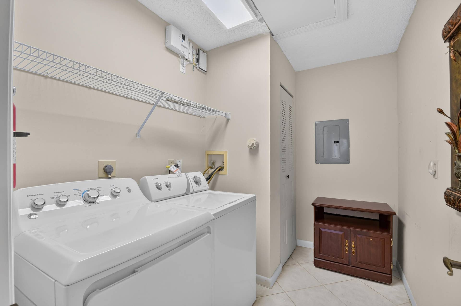 Laundry room featuring tile flooring, a built-in wire shelving unit, and overhead lighting