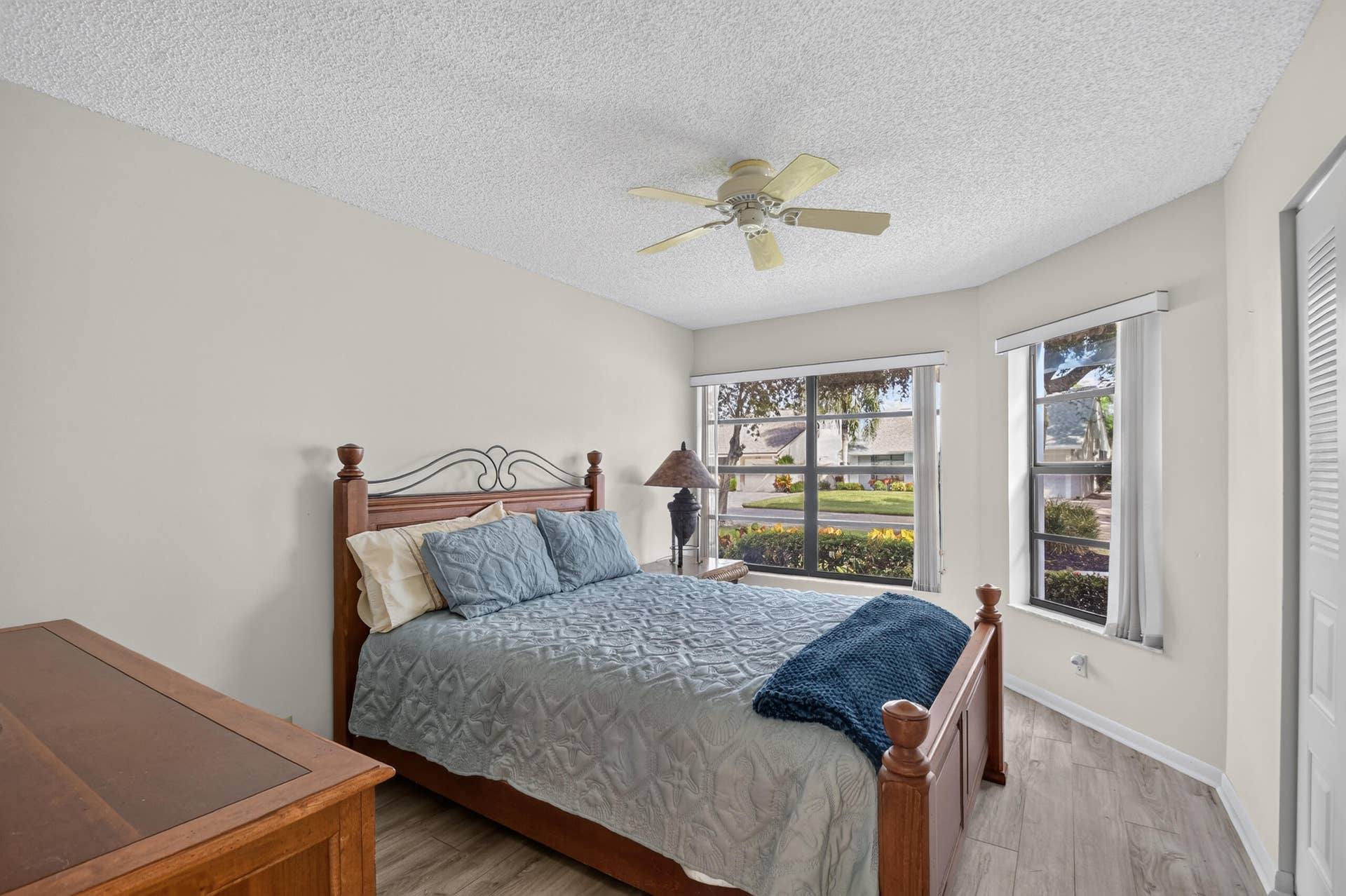 Wood-finish flooring, ceiling fan with integrated lighting, and dual windows with horizontal blinds
