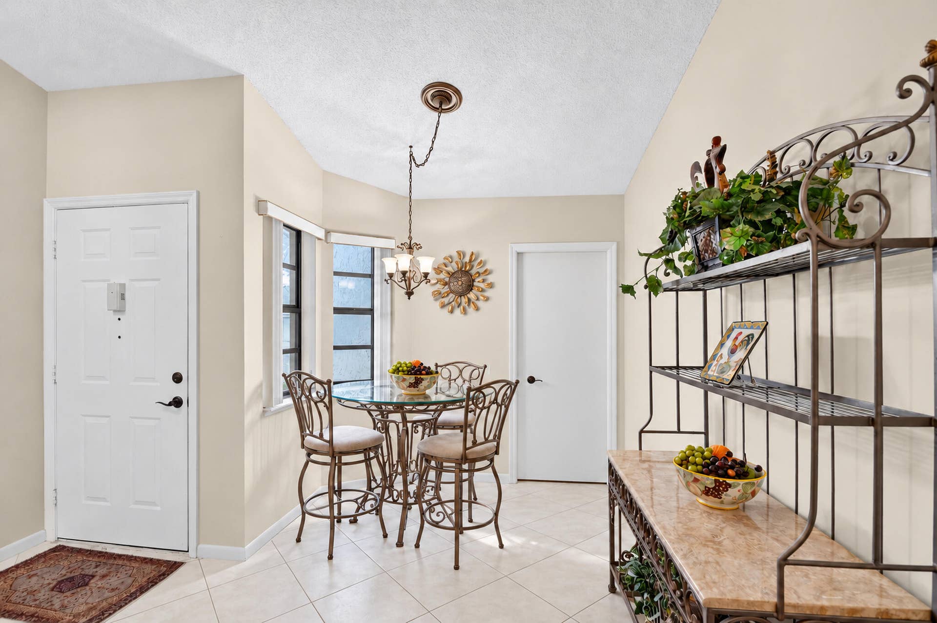 Tiled flooring, vaulted ceilings, and multi-pane windows with a hanging chandelier fixture