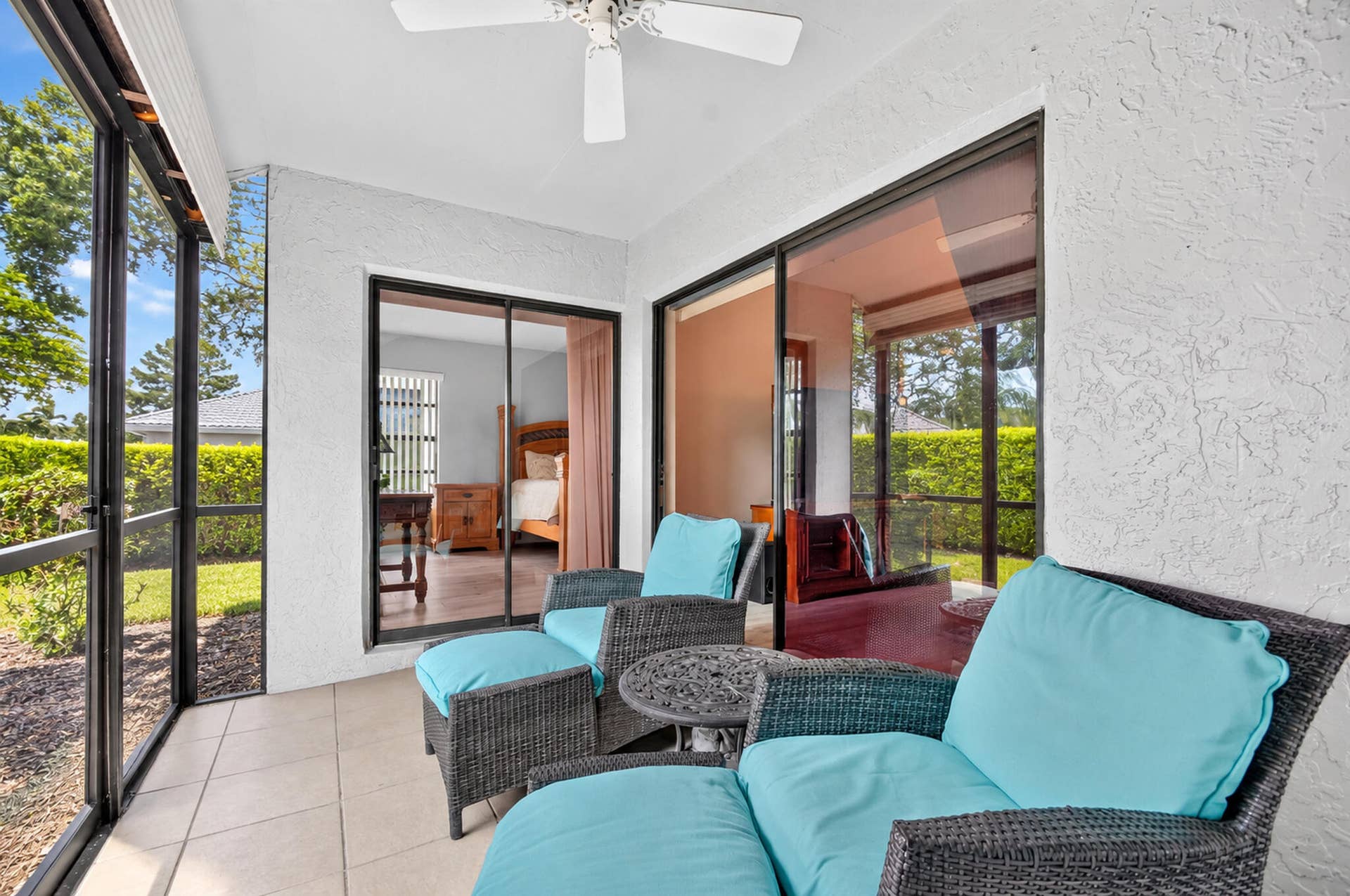 Screened-in porch featuring tile flooring, a white ceiling fan, and large sliding glass door entries