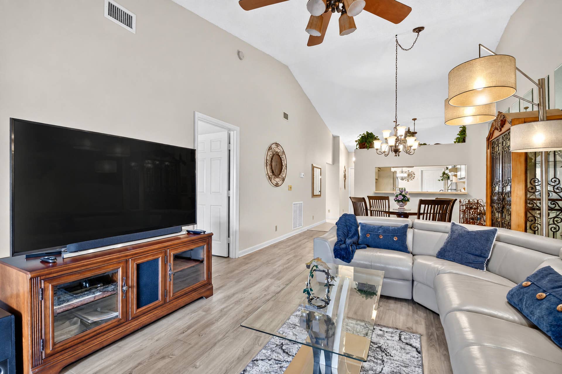 Vaulted ceilings, wood-finish flooring, recessed lighting, and a multi-arm chandelier