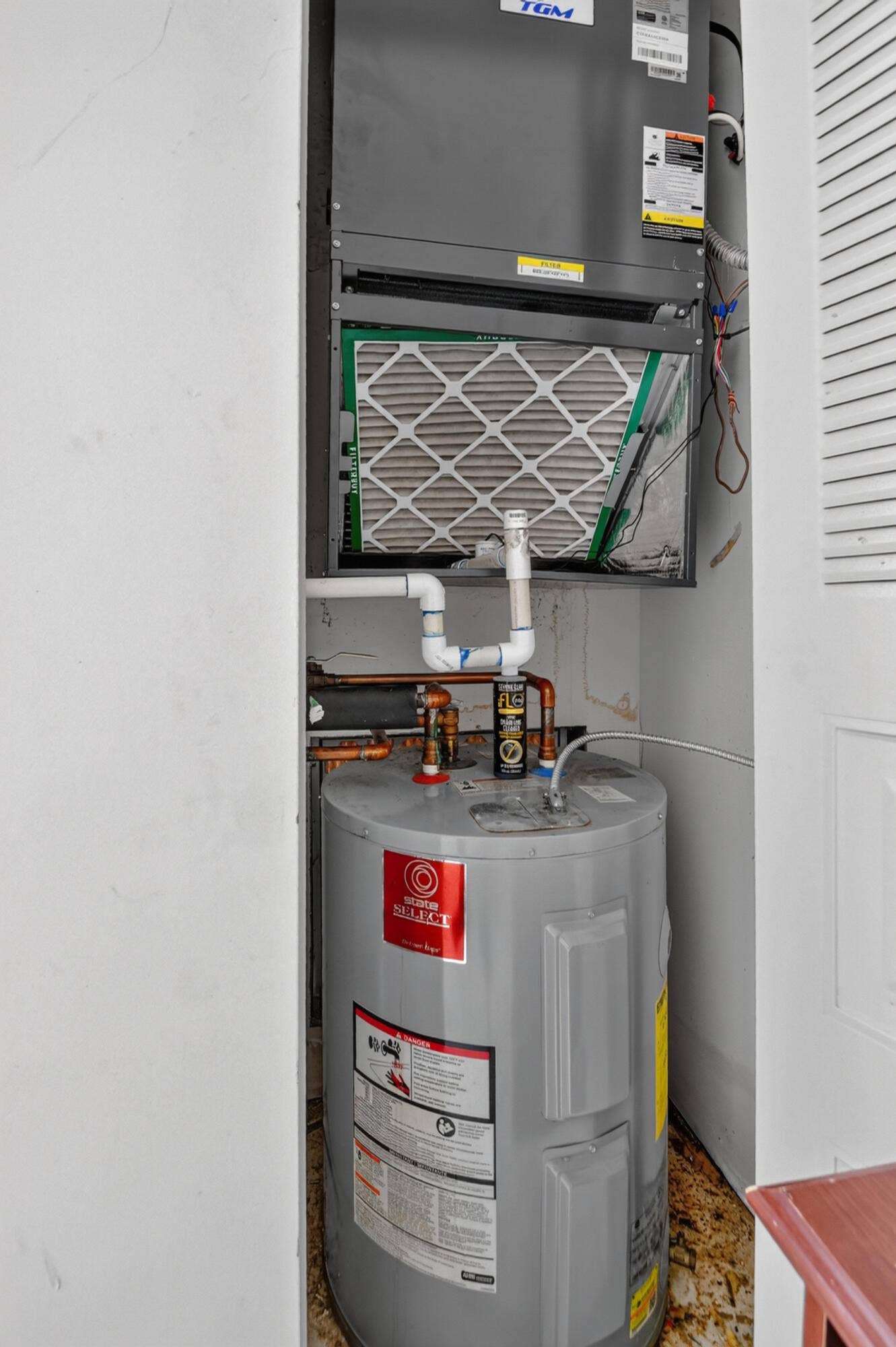 Utility closet featuring a TGM air handler unit and a Rheem water heater