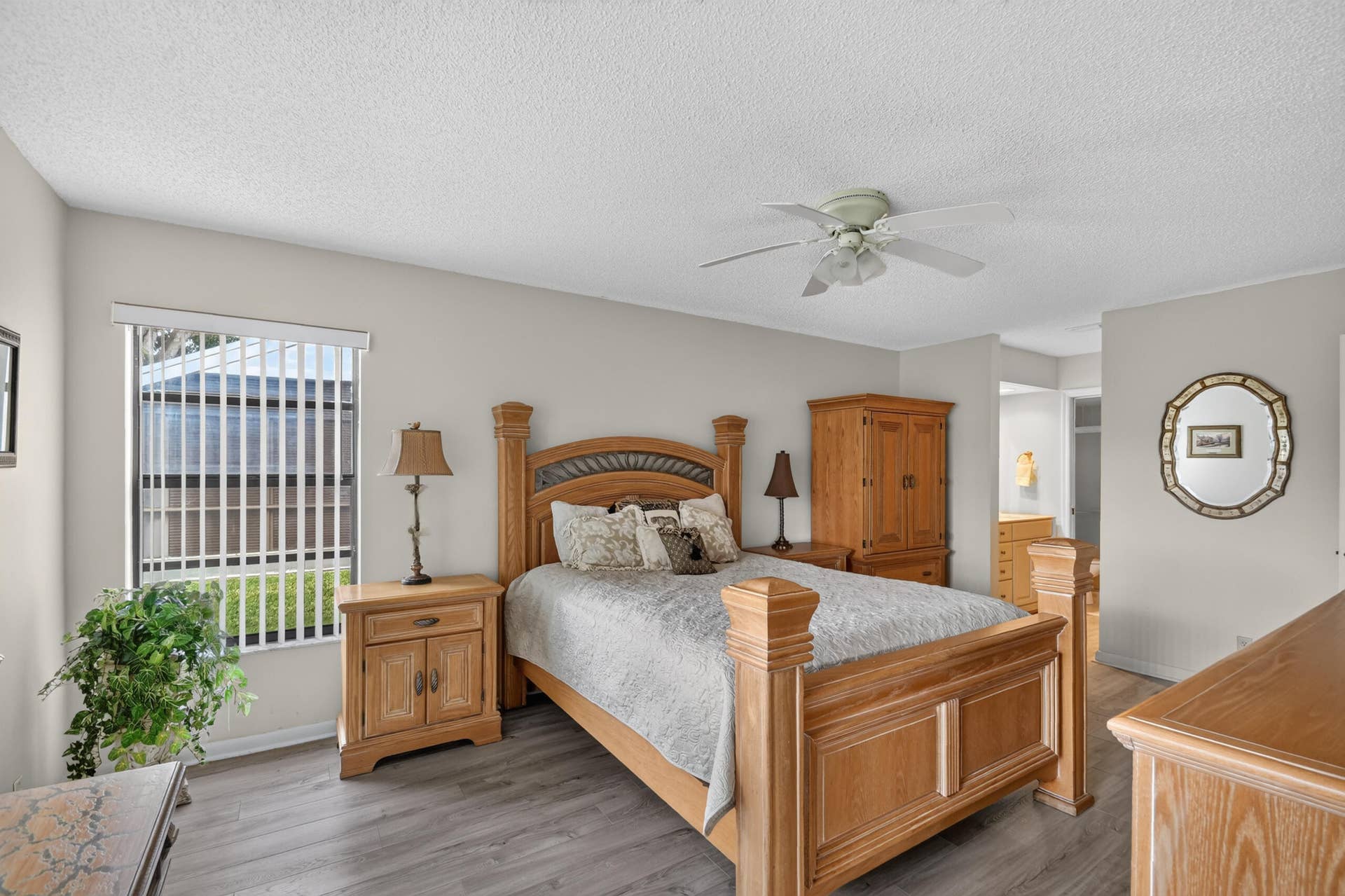 Neutral-toned walls, wood-finish flooring, ceiling fan, and window with vertical blinds
