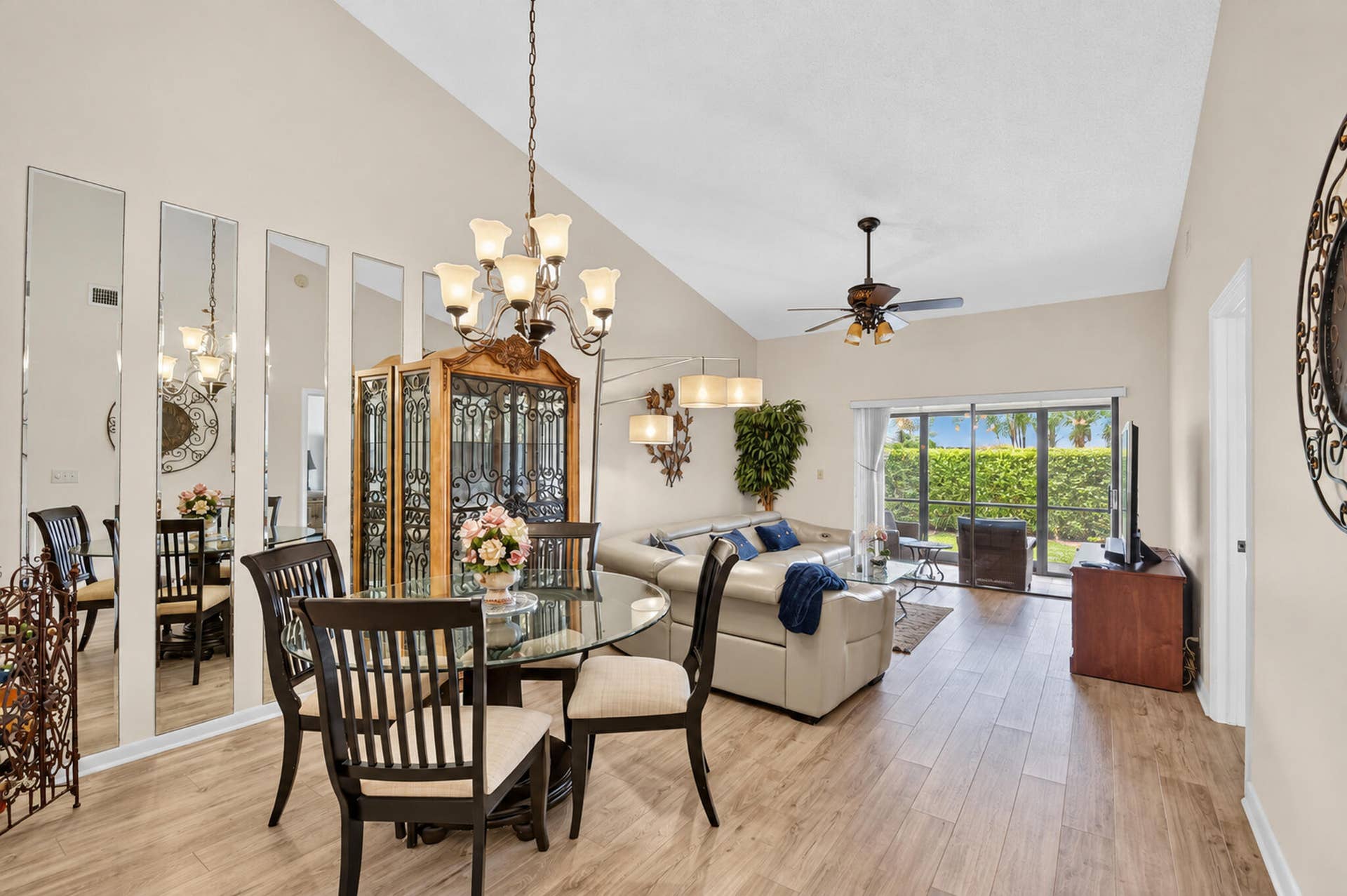 Vaulted ceilings, wood-finish flooring, full-length wall mirrors, multi-bulb chandelier, and sliding glass doors