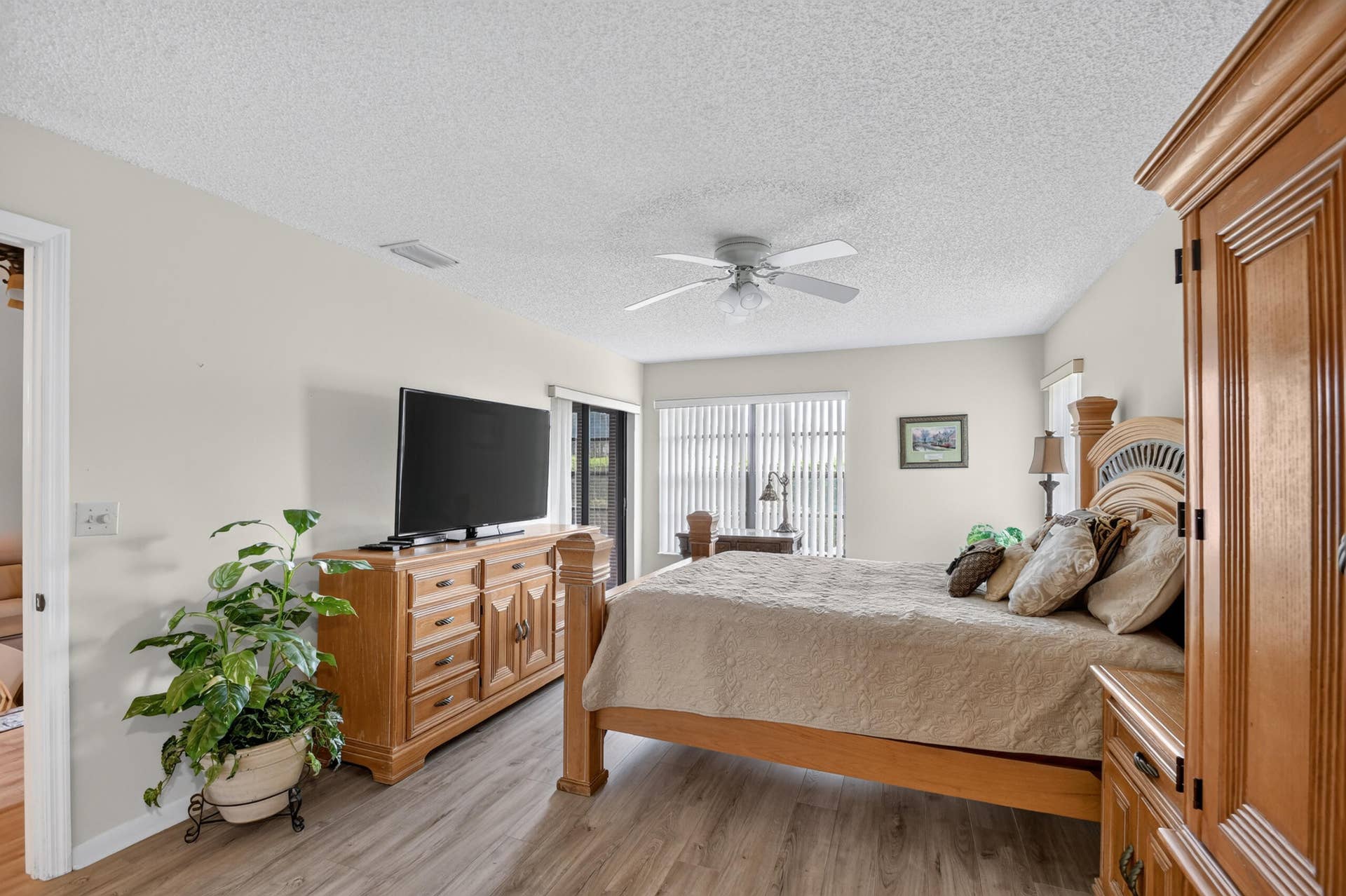 Bedroom featuring wood-finish flooring, a ceiling fan with integrated lighting, and vertical window blinds