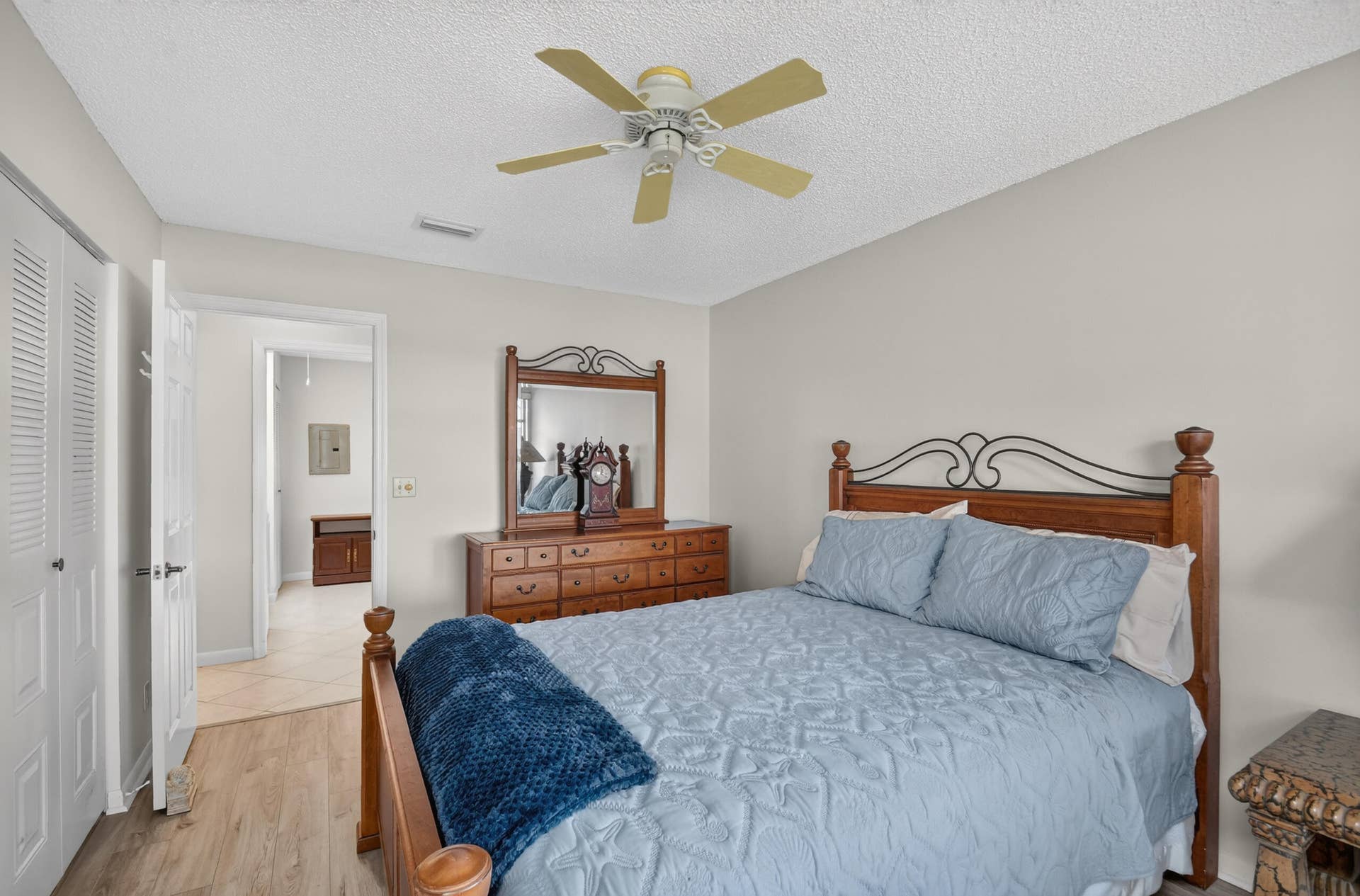 Neutral-toned interior space featuring wood-finish flooring, a multi-blade ceiling fan, and louvered double closet doors