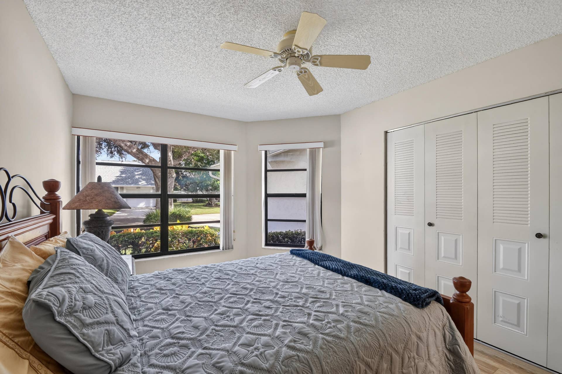 Dual-aspect windows with dark mullions, ceiling fan, and floor-to-ceiling built-in closet with louvered double doors