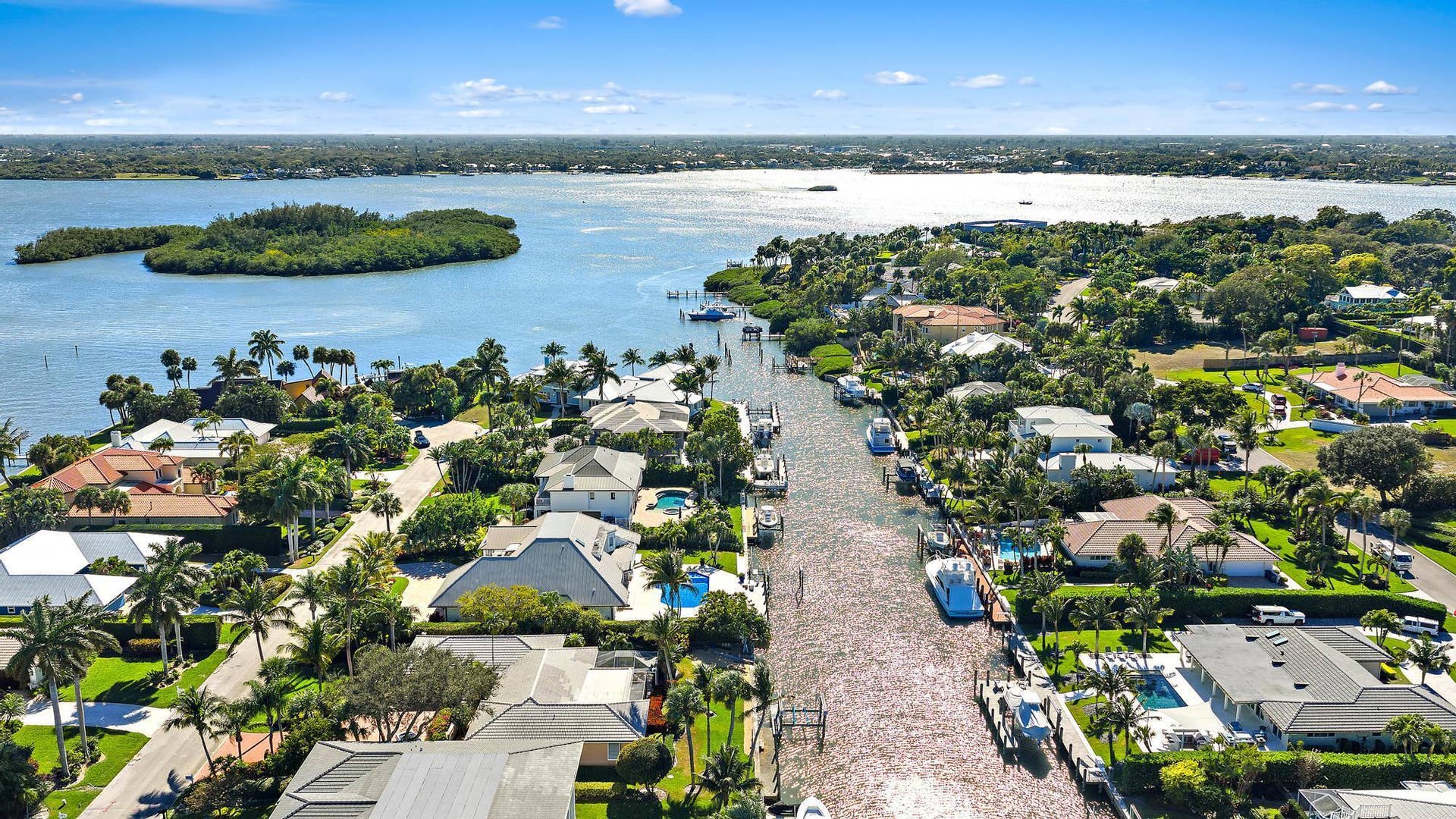 Aerial perspective of a waterfront residential area featuring deep-water canal access, private boat docks, and direct access to open water