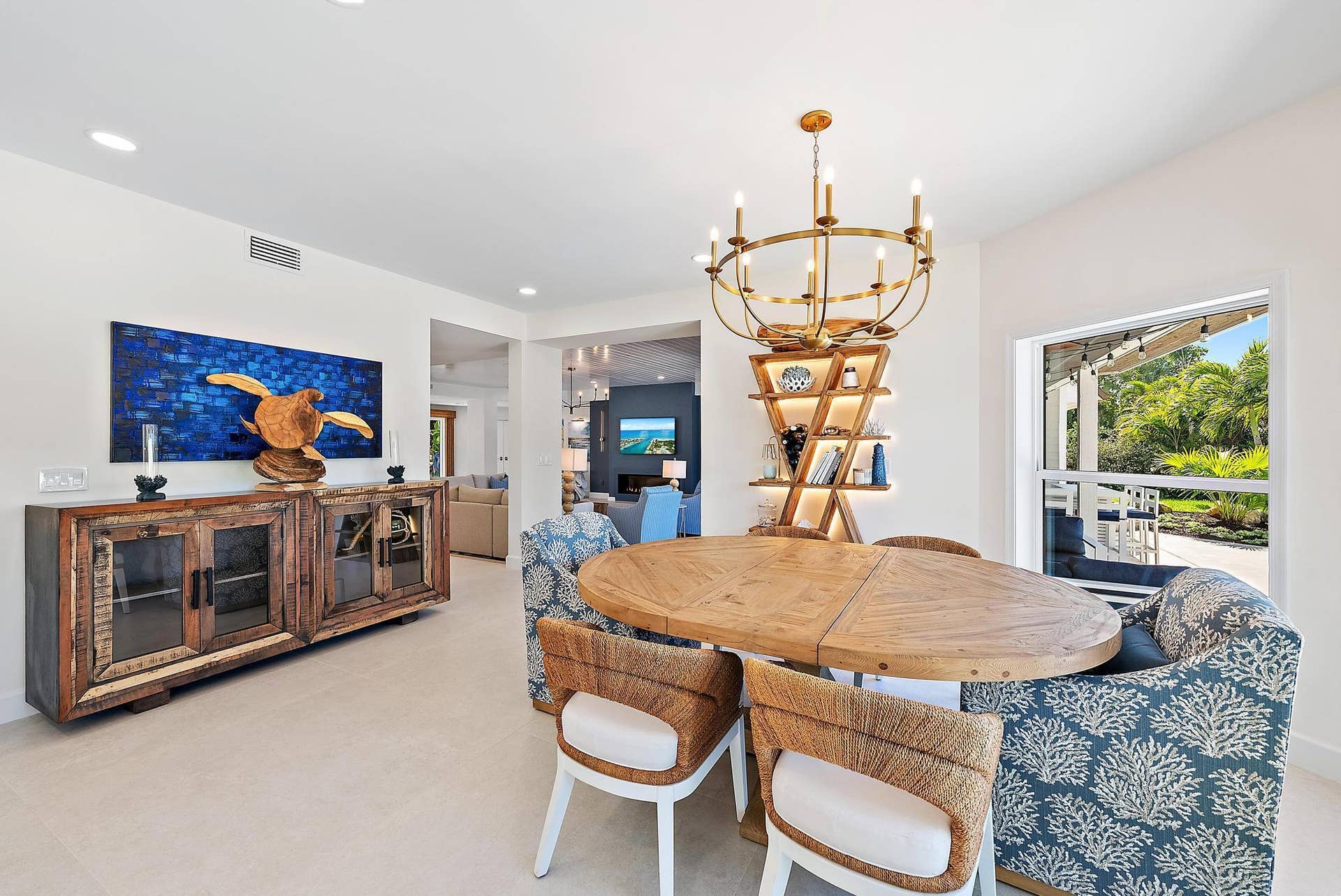 Dining area featuring recessed lighting, a multi-tiered brass chandelier, built-in recessed shelving with integrated lighting, and neutral large-format tile flooring