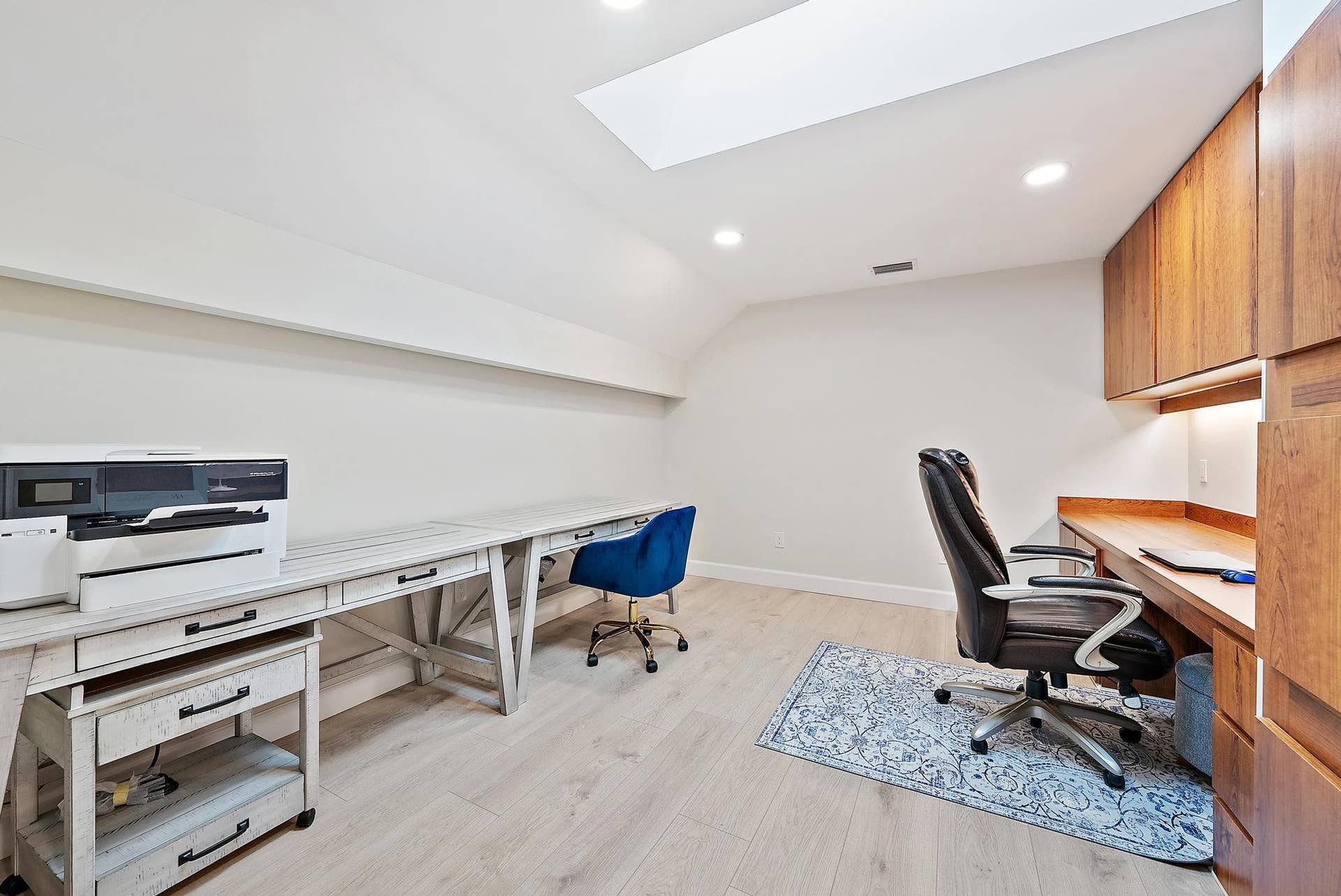 Skylight, wood-finish flooring, recessed lighting, and wall-to-wall built-in cabinetry with under-cabinet lighting