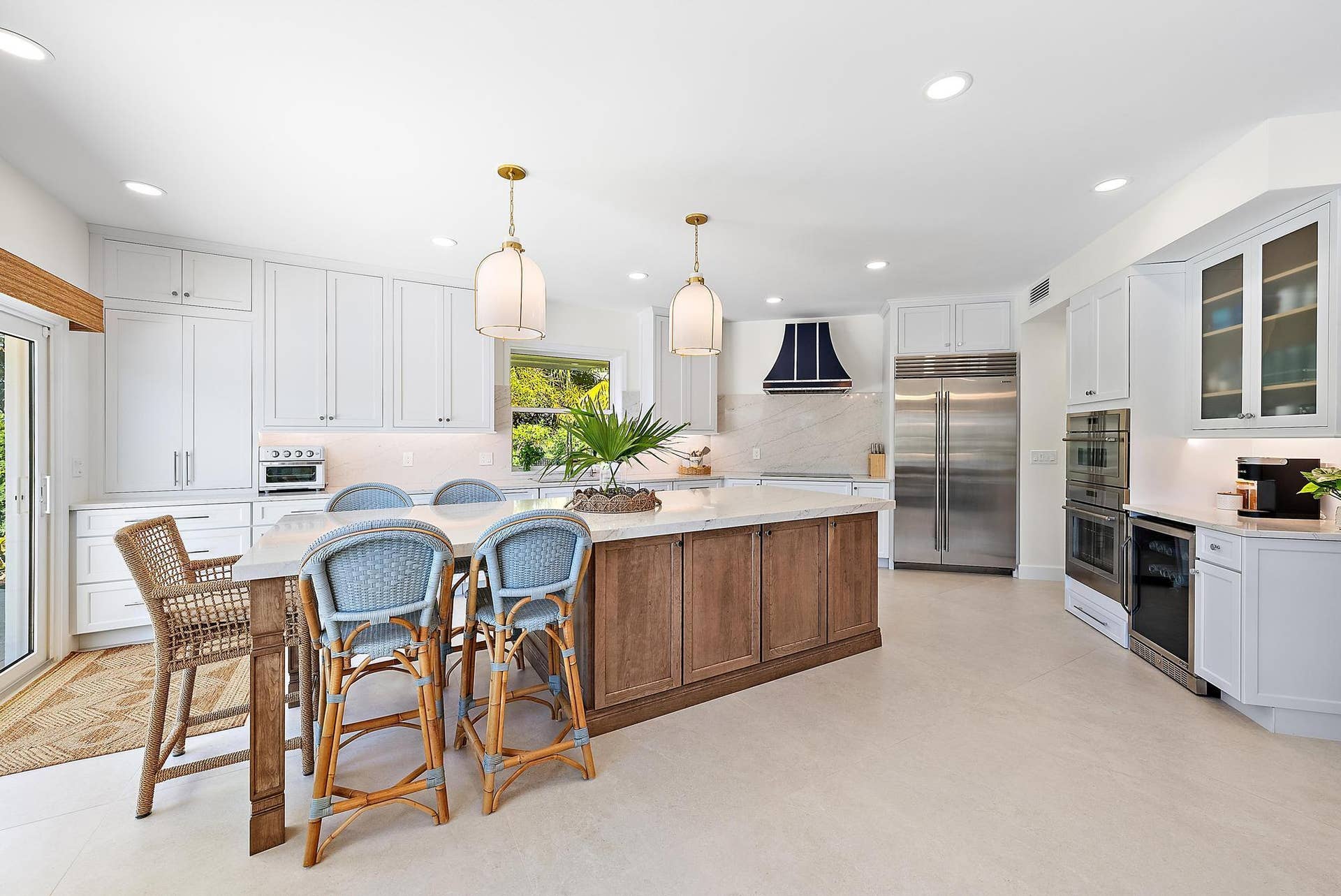 Kitchen featuring white cabinetry, a wood-finish central island with a stone countertop, stainless steel double-door refrigerator, built-in double ovens, and decorative pendant lighting