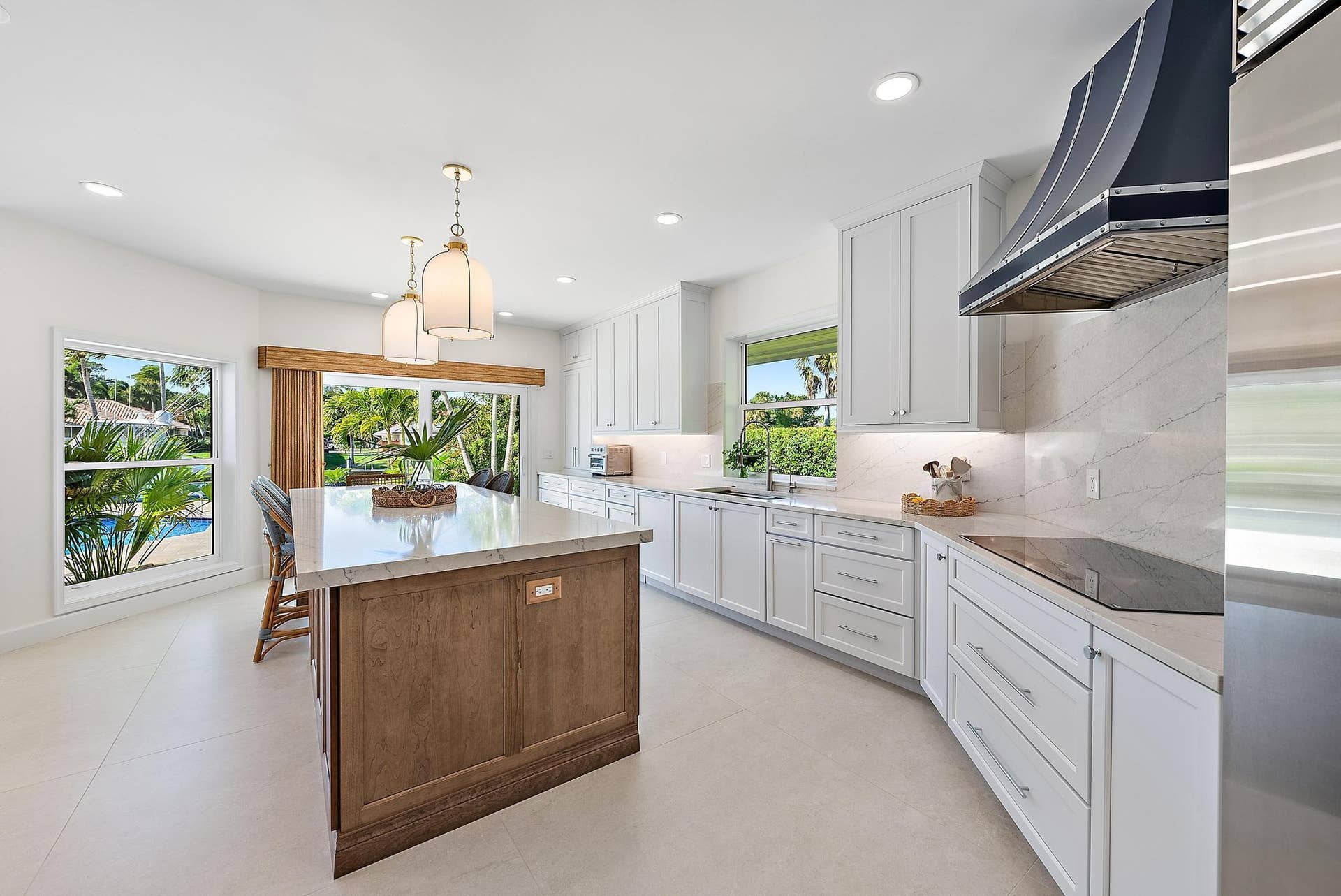 Kitchen featuring a central island with wood-finish cabinetry, quartz countertops, white Shaker-style cabinetry, a custom metal range hood, and recessed lighting