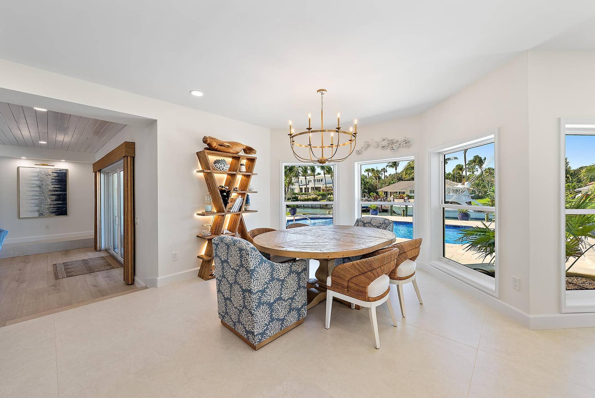 Dining area featuring large-format tile flooring, a multi-arm brass chandelier, multiple floor-to-ceiling windows, and recessed lighting