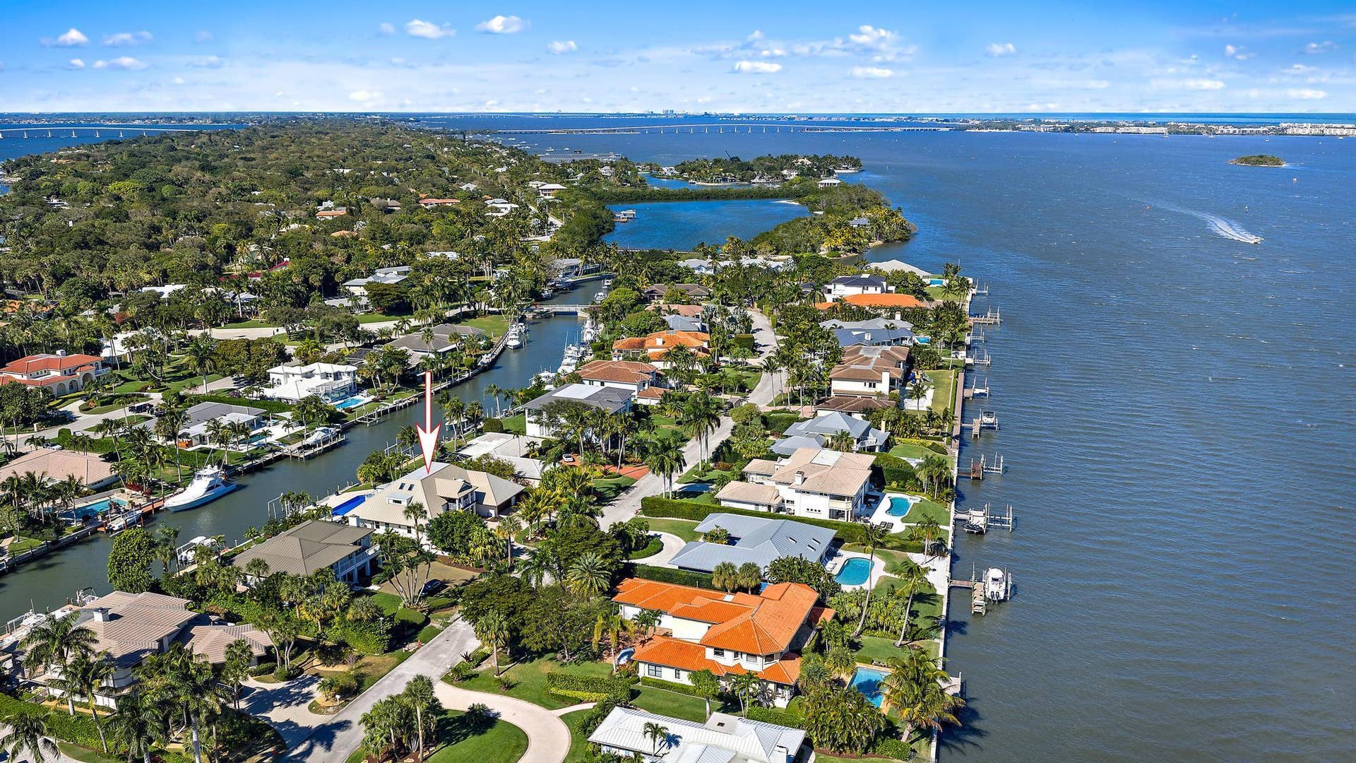 Waterfront property featuring a canal-side bulkhead, multi-level architectural design, and mature coastal landscaping