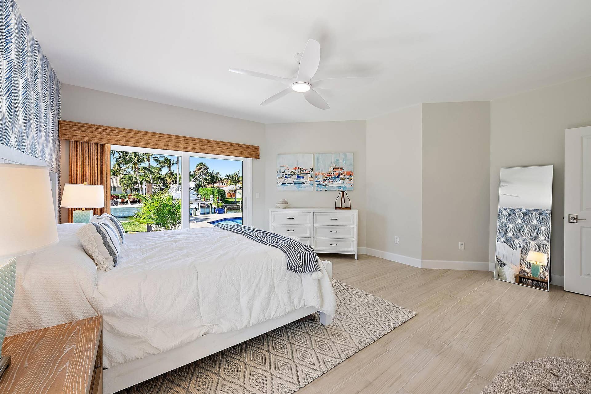 Large sliding glass door featuring integrated bamboo-finish valance, wood-finish flooring, and white multi-blade ceiling fan with light fixture