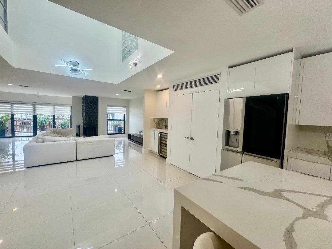 1127 BOCA COVE Lane, Highland Beach, FL 33487 Spacious open-concept living area featuring high ceilings, a stone-clad fireplace, and large glass doors