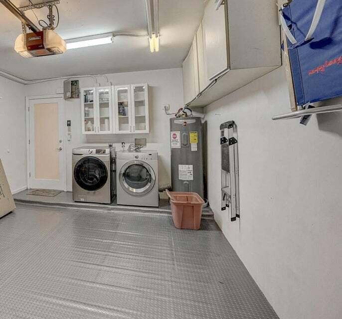 1127 BOCA COVE Lane, Highland Beach, FL 33487 Garage space featuring textured flooring, overhead cabinetry, and built-in laundry appliances